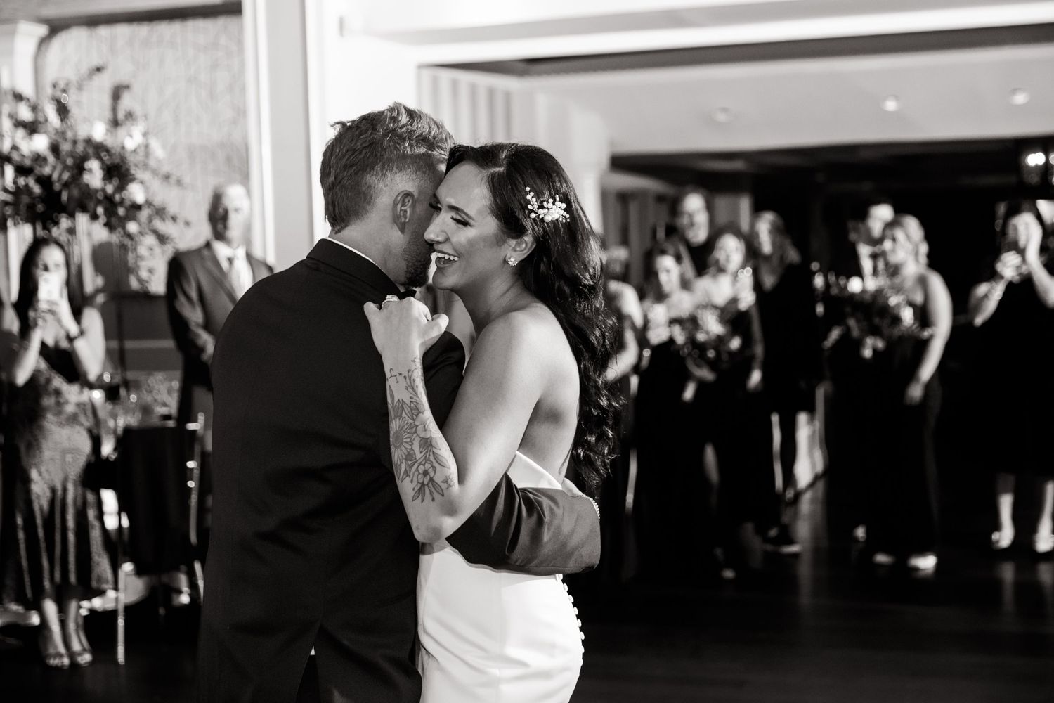 A couple shares their first dance at an elegant wedding reception surrounded by guests.
