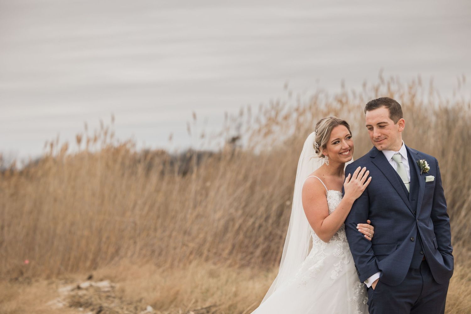 Couple in wedding attire sharing sweet moment against rustic autumn landscape.
