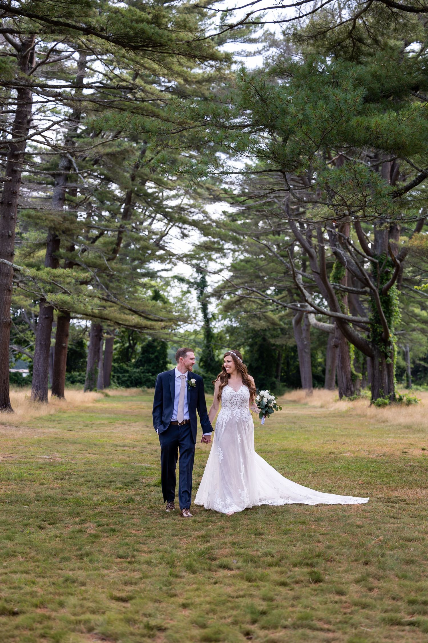 Wedding couple walks hand in hand through majestic pine forest.