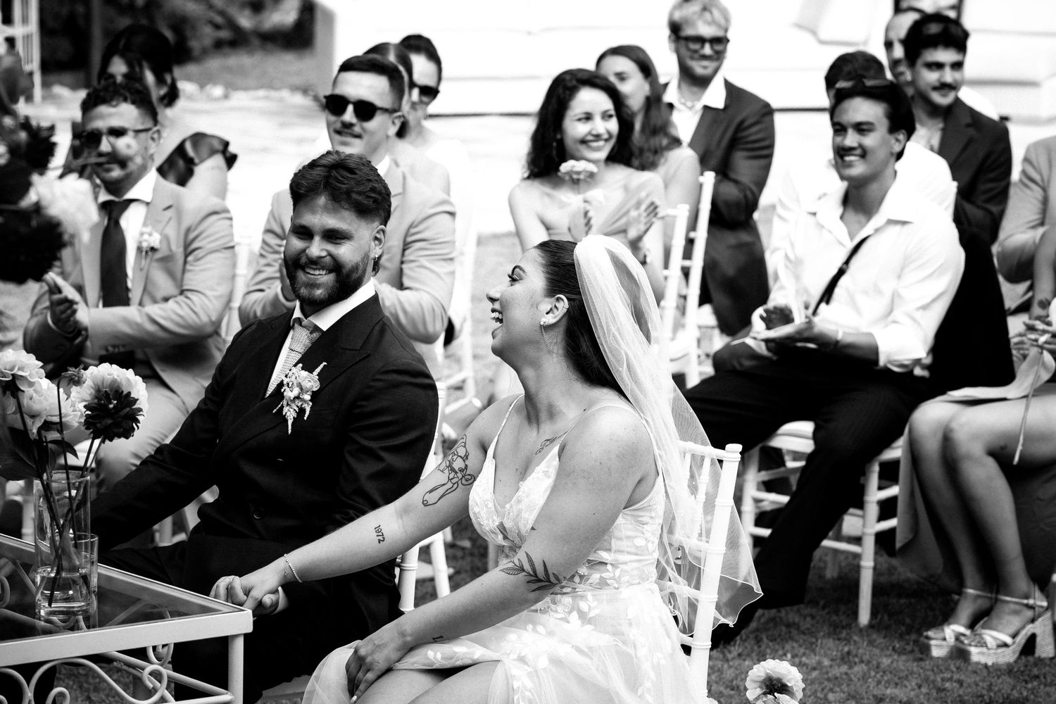 A collection of black and white candid wedding photos showing joyful moments between guests and the wedding party.