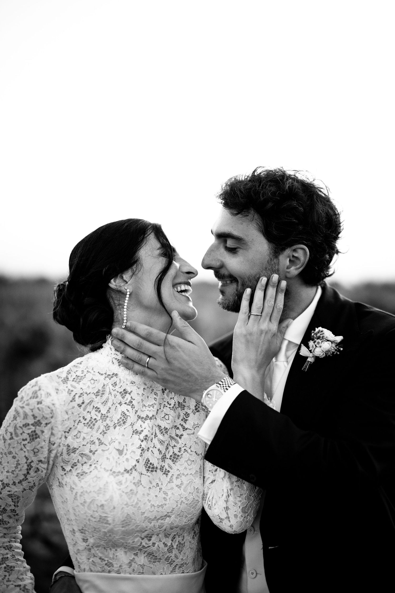 Black and white photo of a laughing bride and groom sharing a tender moment on their wedding day.