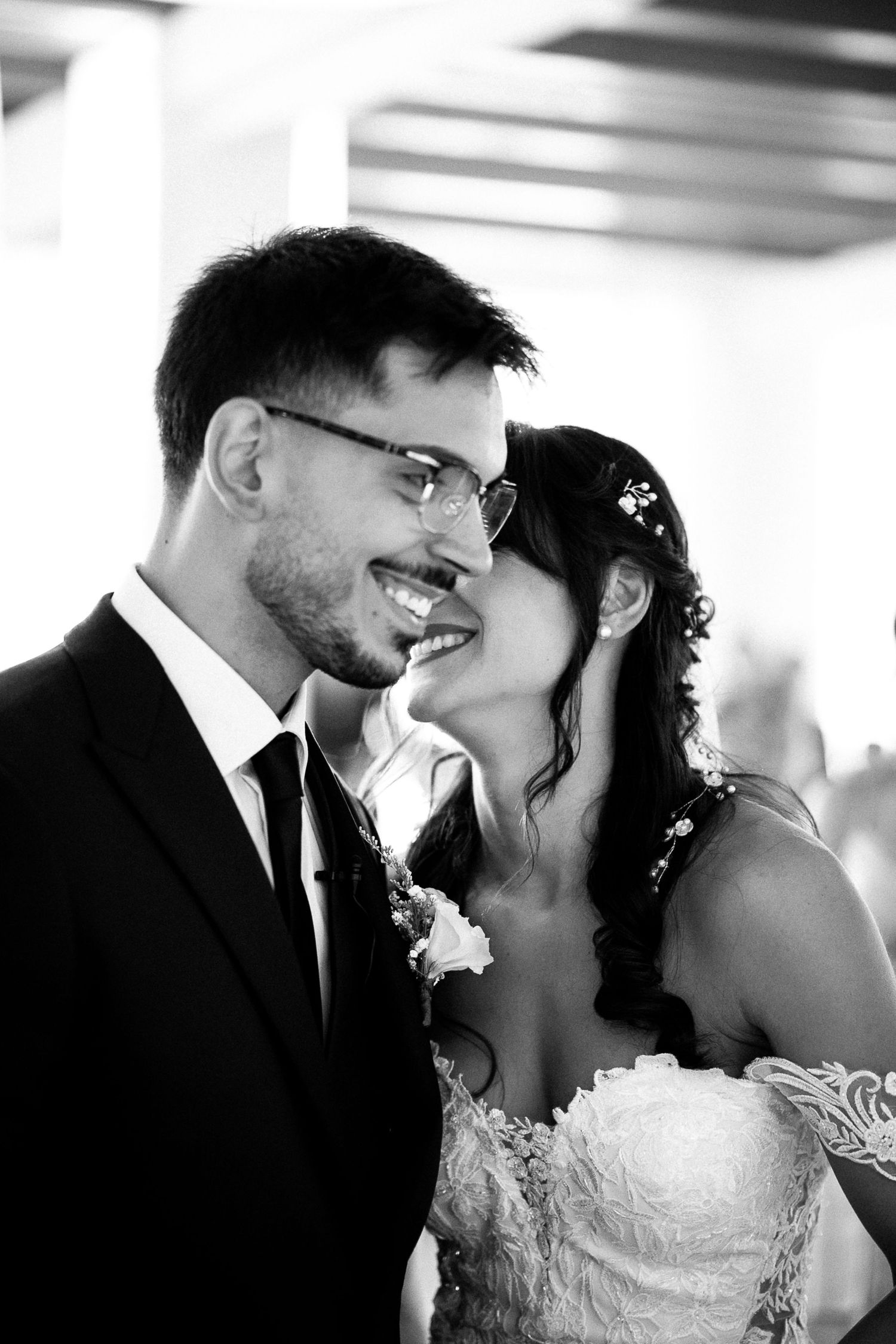 Black and white photo of a smiling bride and groom sharing an intimate moment on their wedding day.
