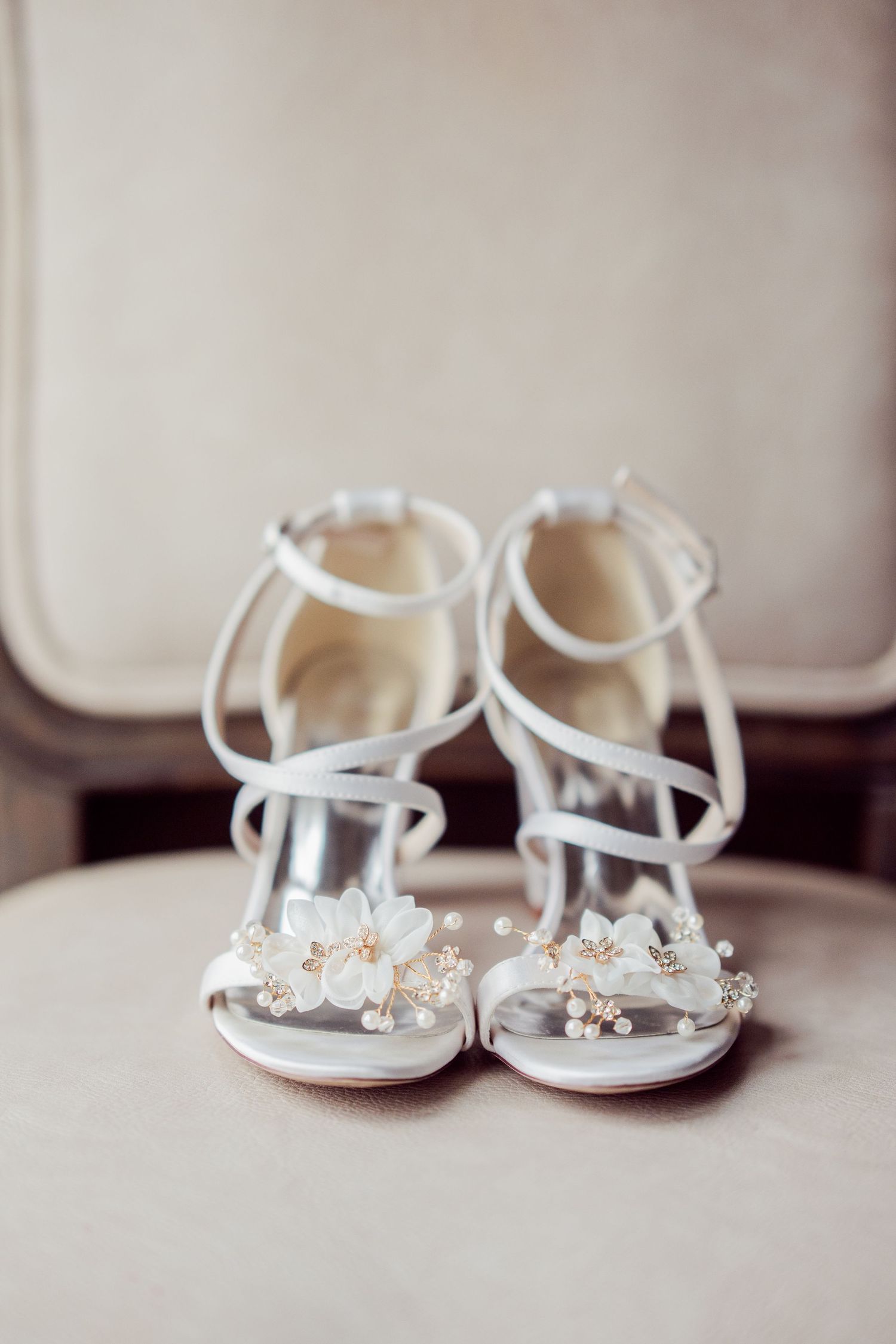 Delicate white bridal sandals with floral embellishments arranged in a row.