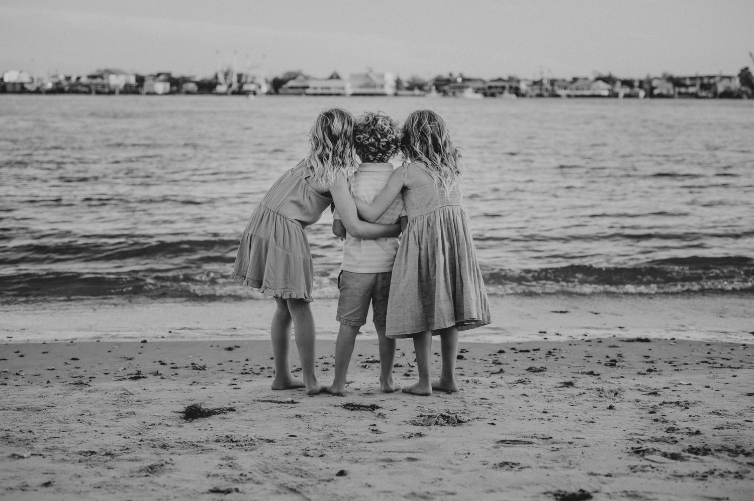 Scenic coastal view with people gathered along the shoreline in black and white.
