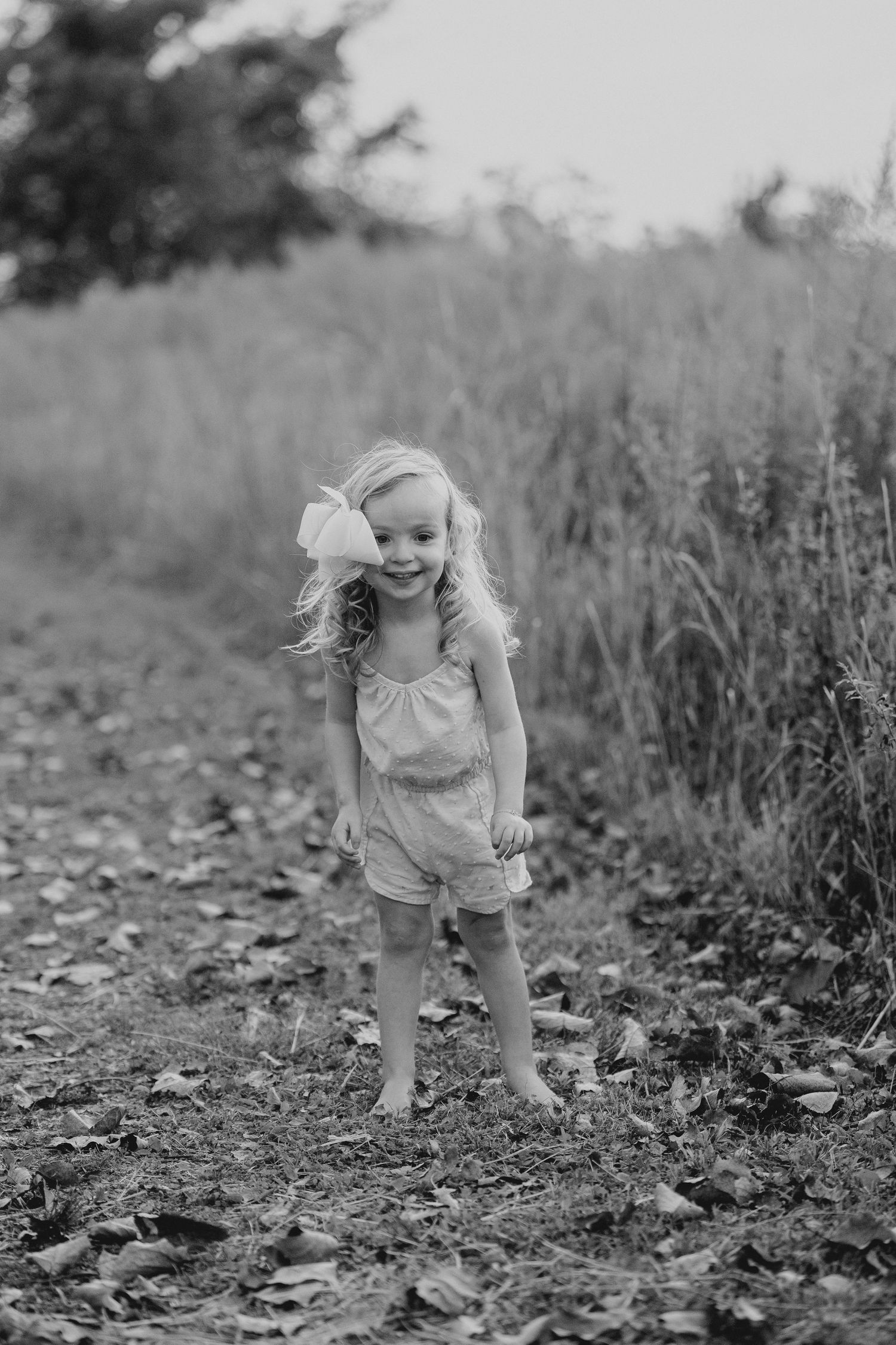 Black and white photo of small child exploring outdoors in casual summer clothing.