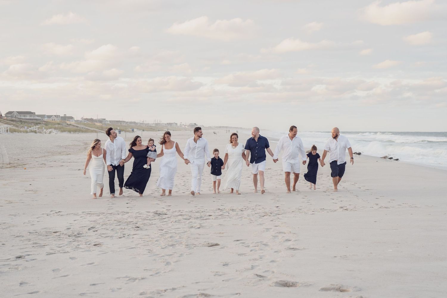 Group walking together along a scenic beach shoreline in coordinated white and blue outfits.