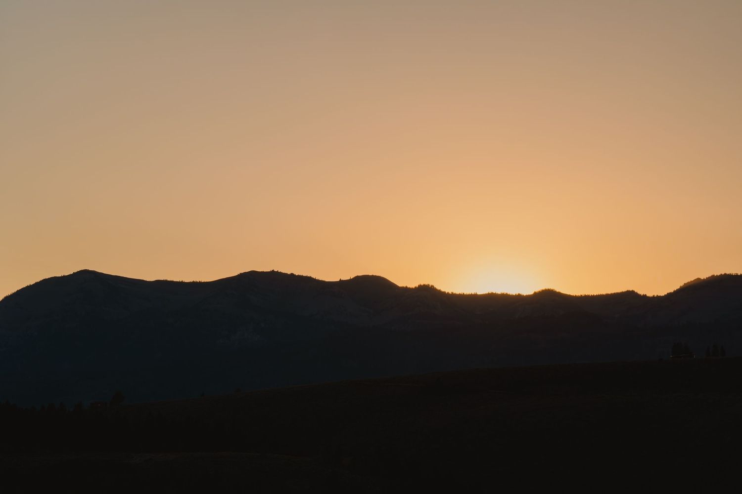 Silhouette of mountain ridge at sunset with golden sky.