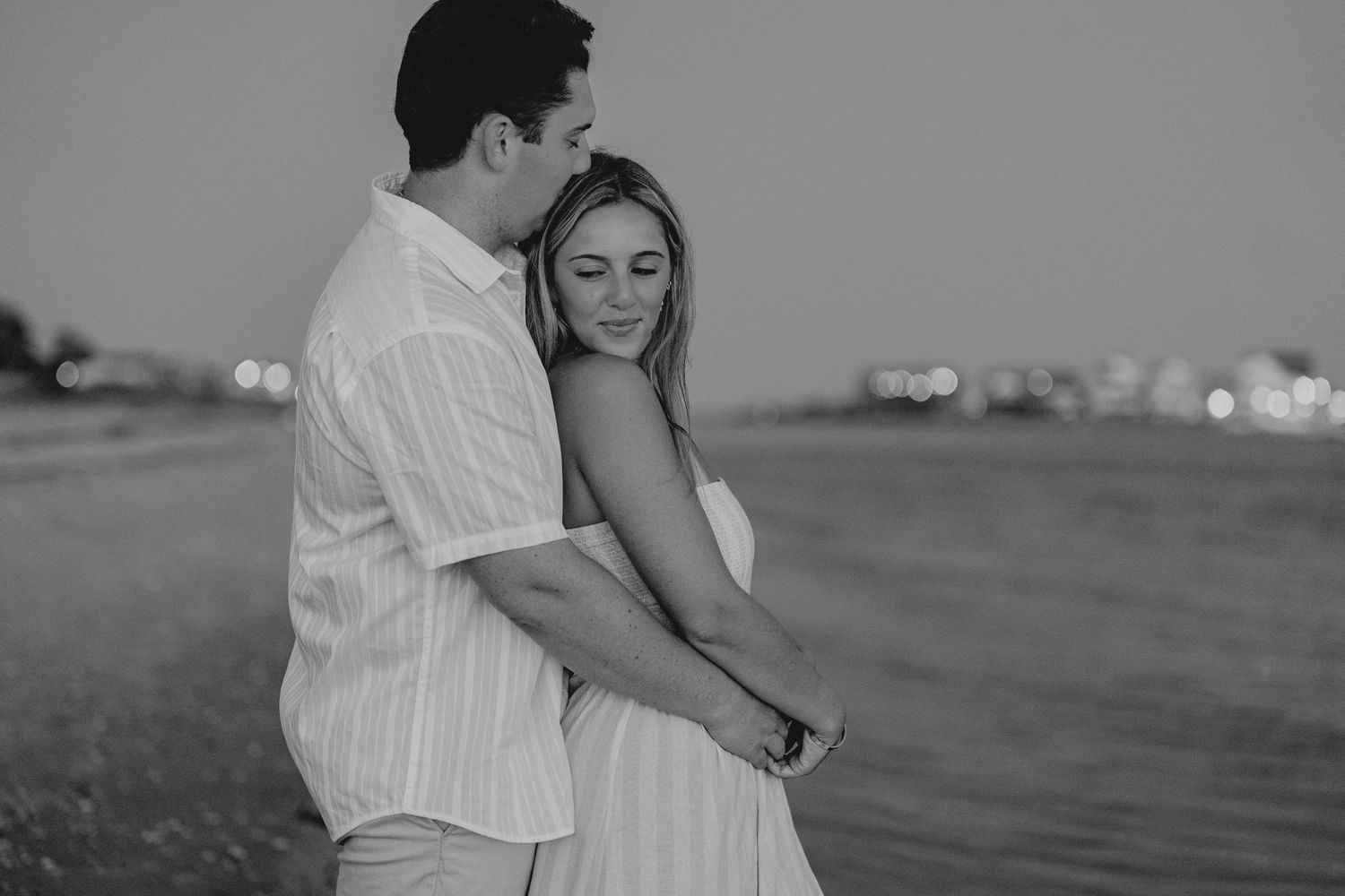 Couple holding hands on a beach at dusk in black and white.
