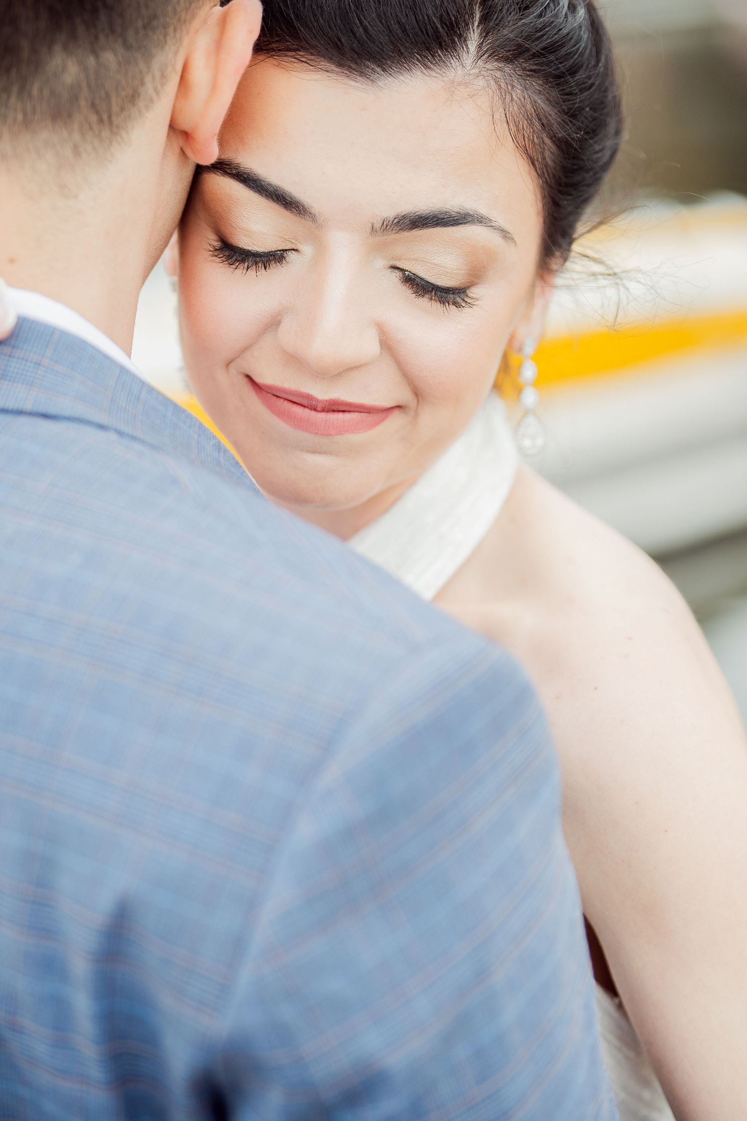 Close-up of a tender wedding moment showing a bride with closed eyes and gentle smile embracing her groom.