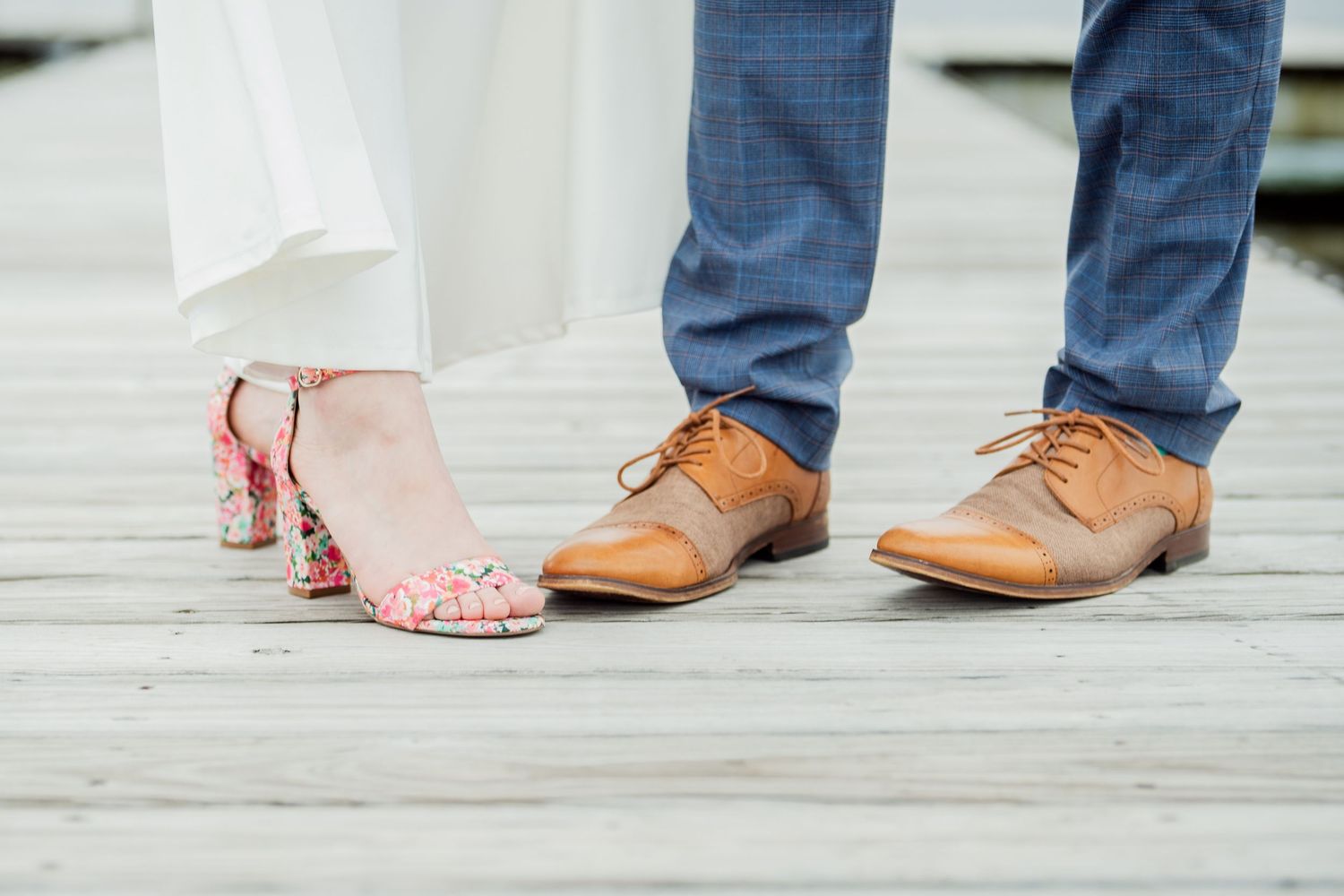 Wedding shoe detail showing bride's pink heels next to groom's brown leather dress shoes.