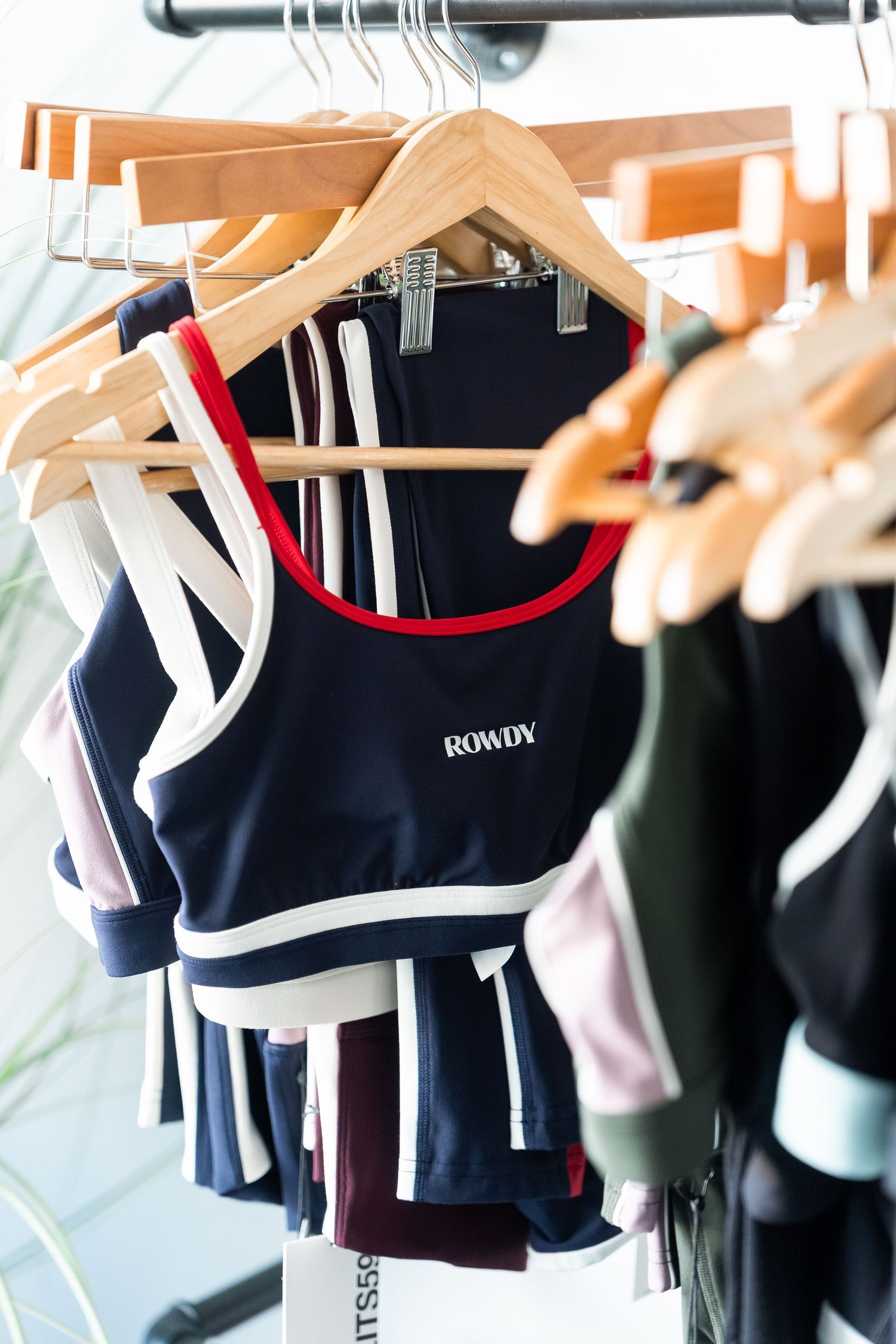 Athletic apparel on hangers displays a collection of black and colored workout clothes.