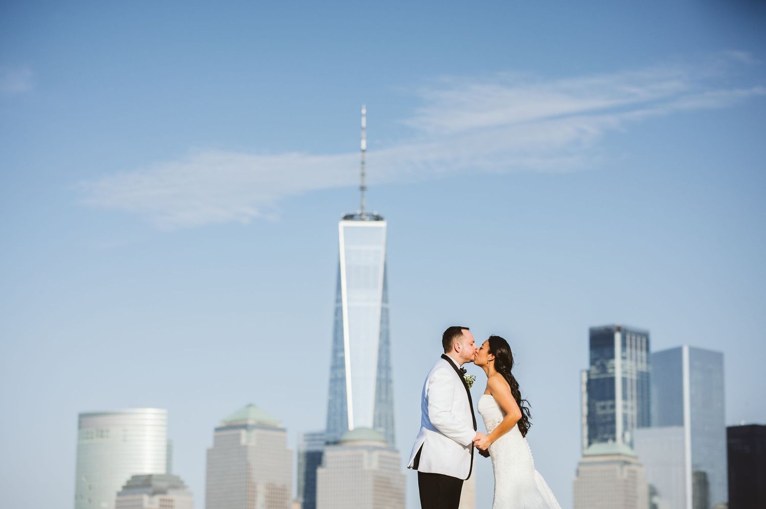 Romantic couple embracing with iconic New York City Freedom Tower and skyline in background.