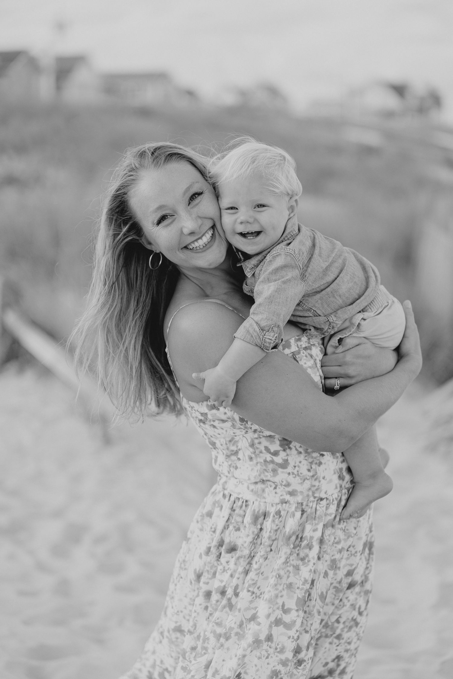 Mother and child share joyful moment on beach in black and white.