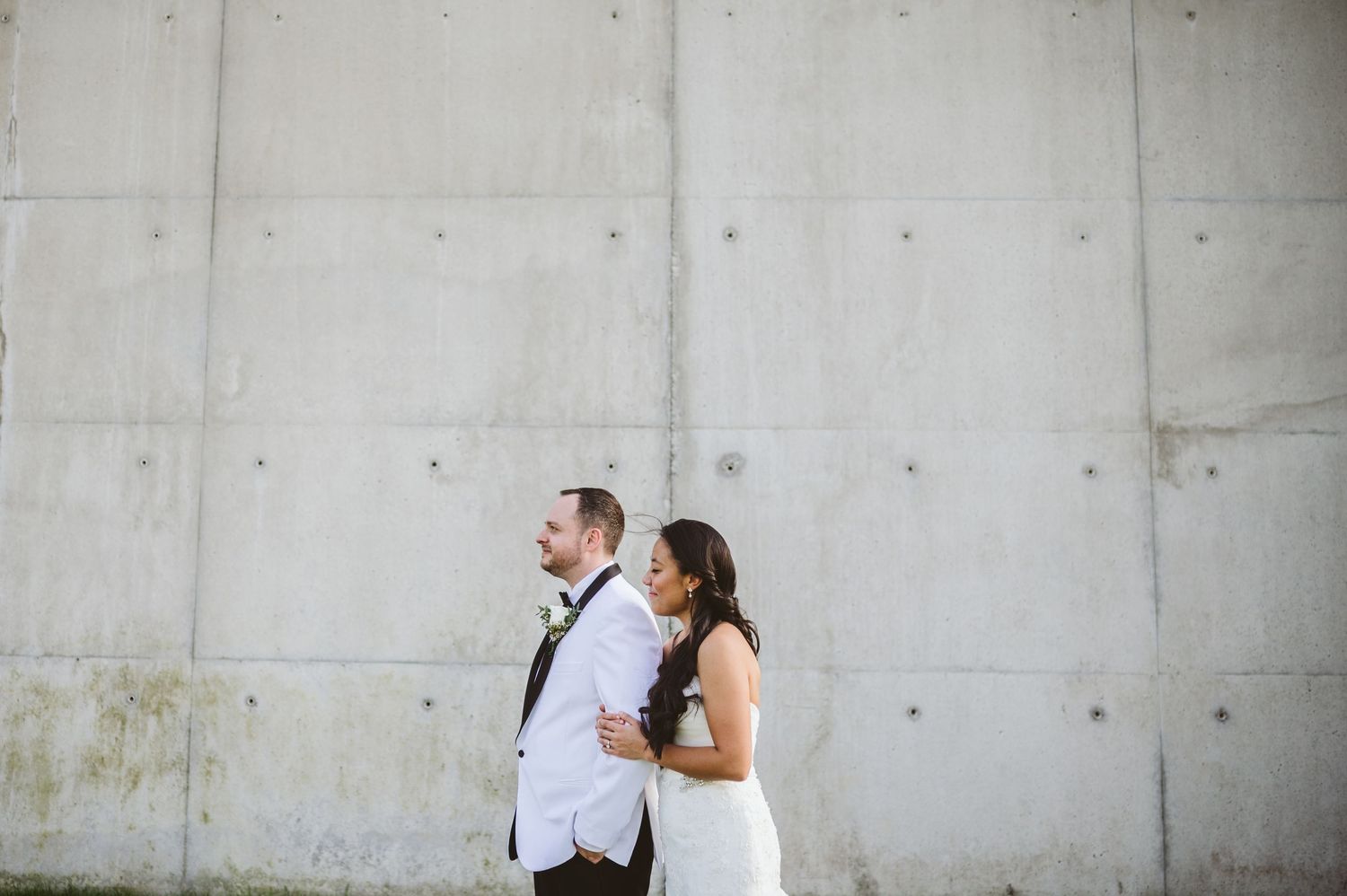 Couple sharing intimate moment against modern concrete wall backdrop.
