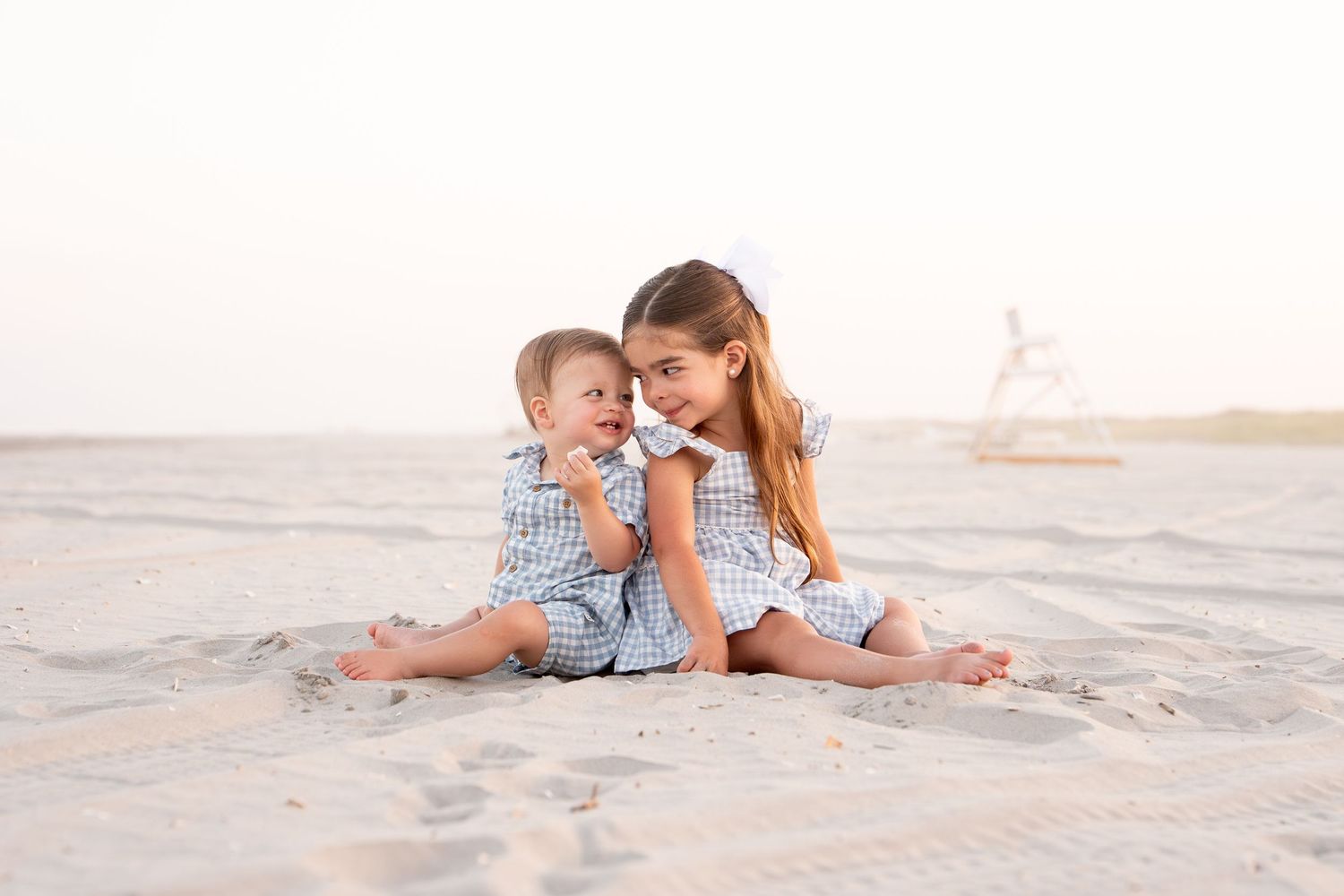 children lounging on sandy beach during golden hour.