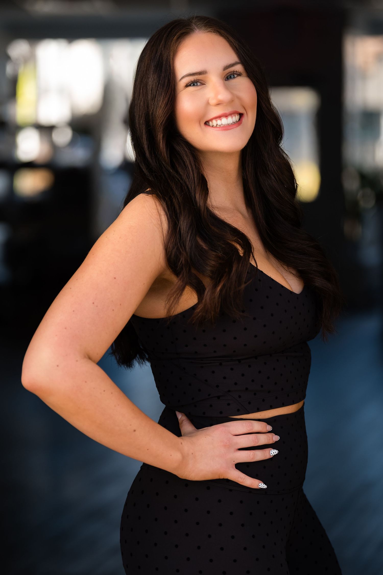 Woman in black dress smiles warmly during outdoor portrait session.