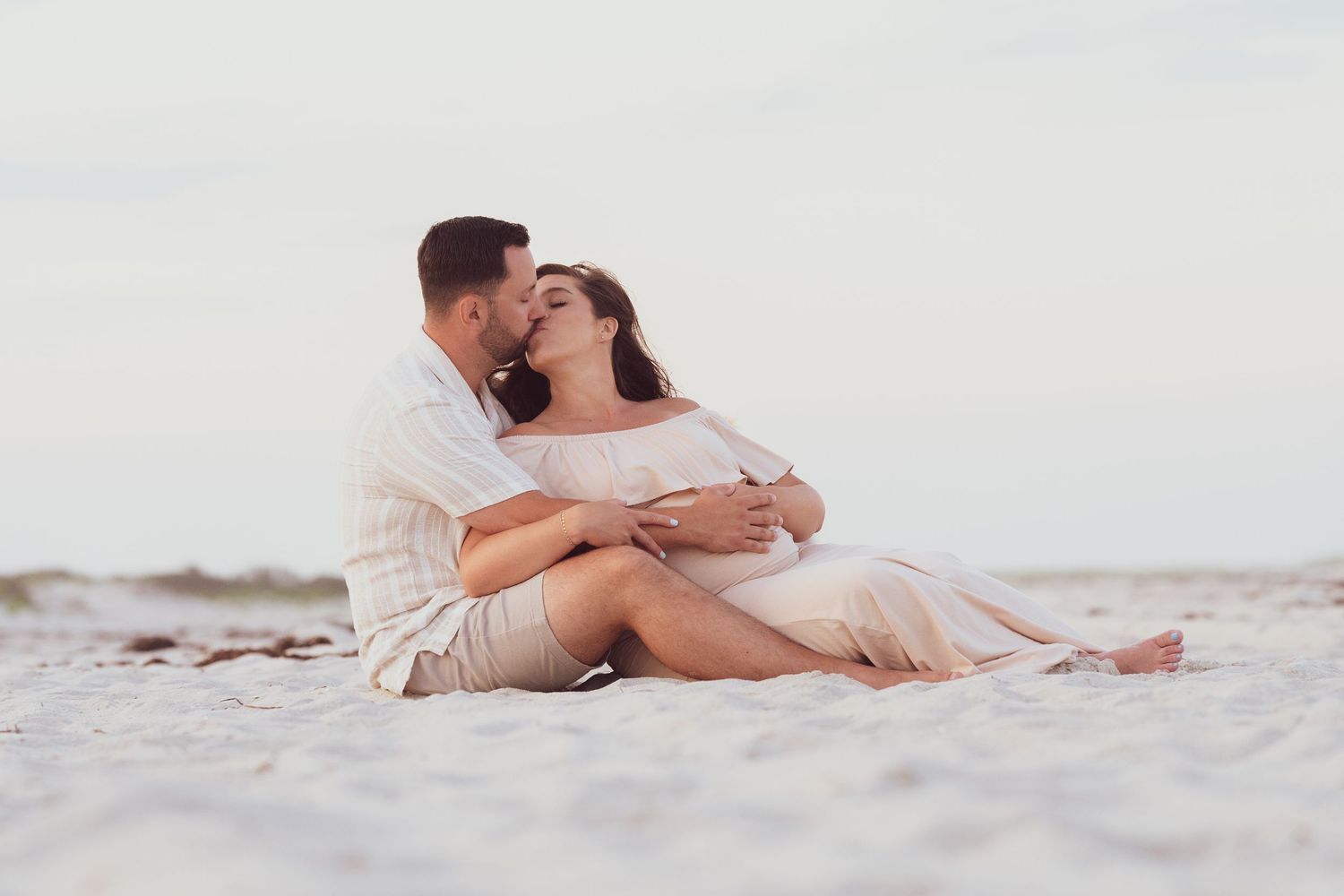 Intimate beach portrait of couple embracing on white sand.