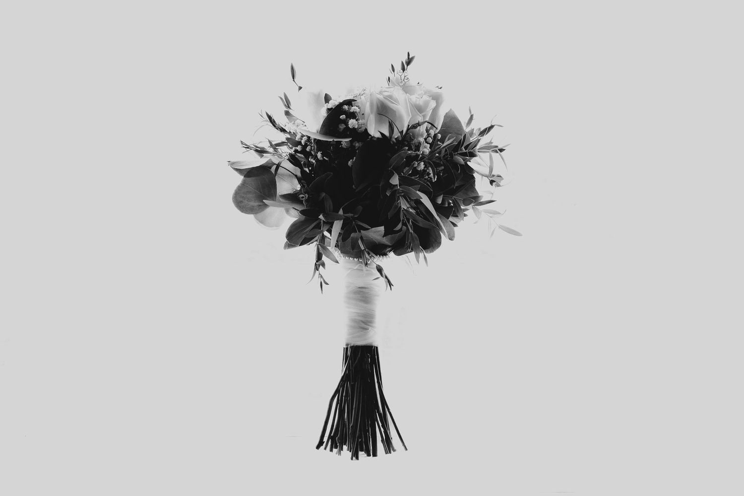 Black and white photo of an elegant wedding bouquet with wrapped stem against light background.