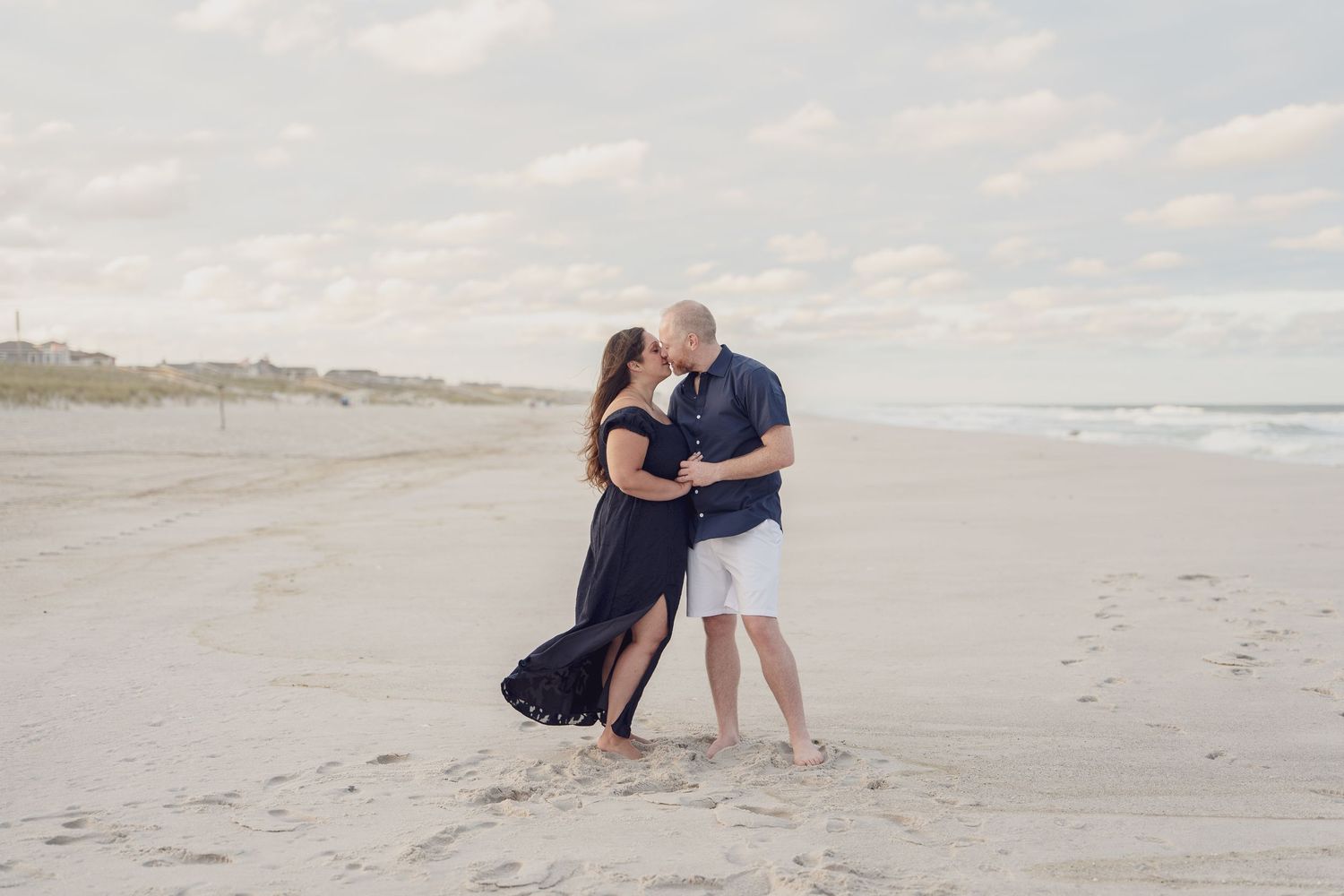 Couple embracing on beach during golden hour photography session.