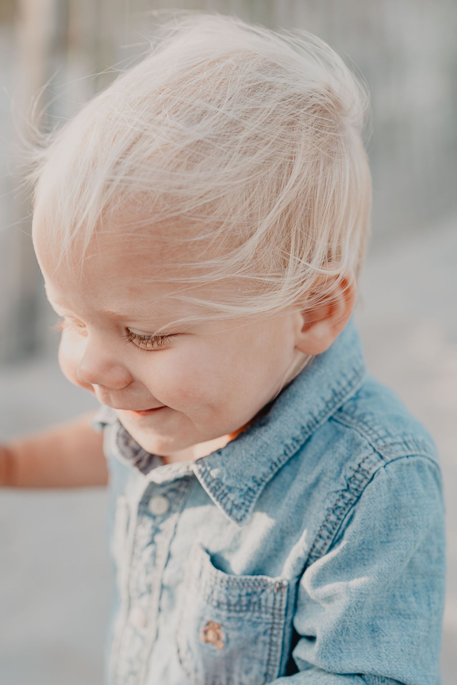 Close-up profile of toddler wearing denim jacket in soft lighting.