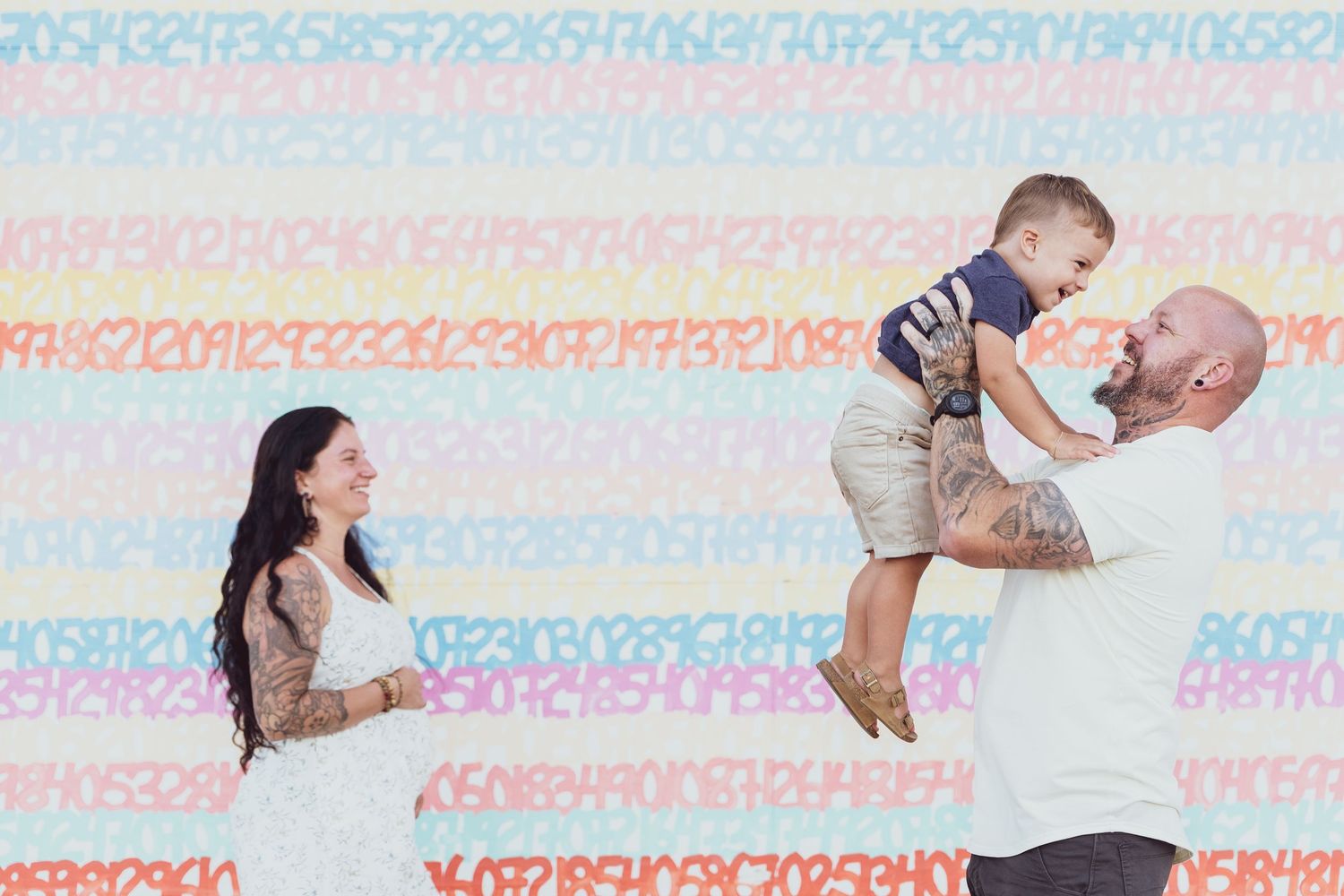 A family poses against a colorful striped background during a playful photo session.
