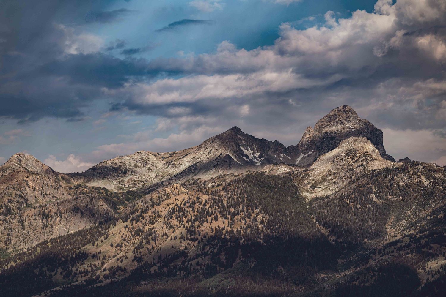 Rugged mountain peaks with dramatic cloud formations in warm afternoon light.
