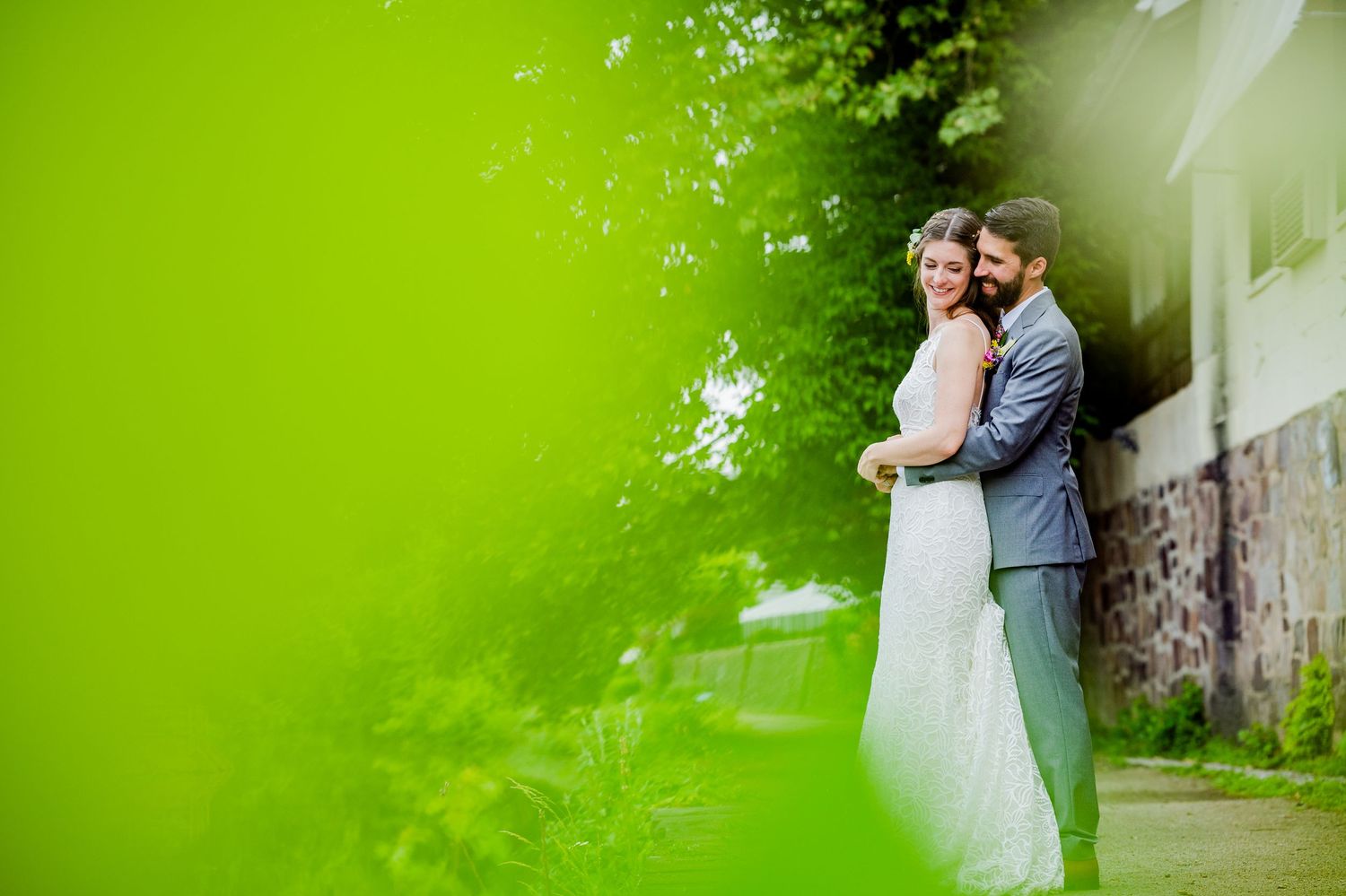 Wedding couple poses in front of vibrant green foliage for romantic portraits.