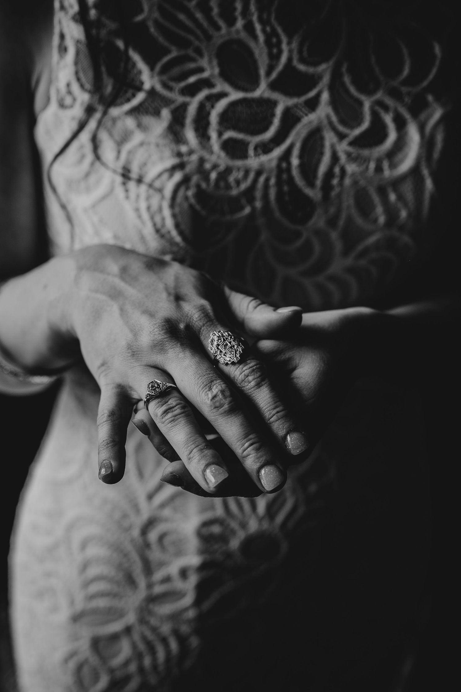 Artistic black and white close-up of hands with delicate lace details.