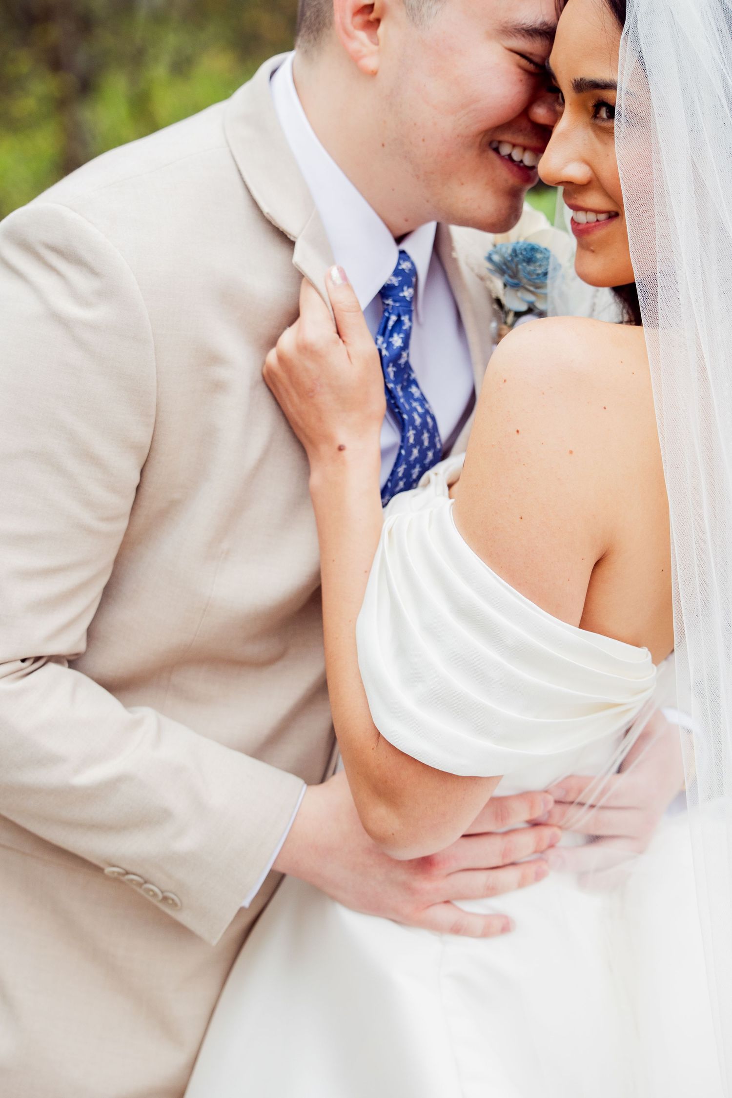 Intimate wedding portrait of couple embracing in tan and white attire.