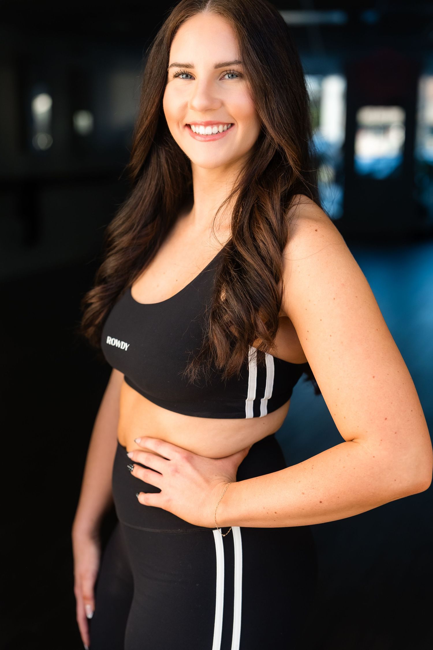 Athletic wear featuring black sports bra and striped leggings shown in a dark studio setting.