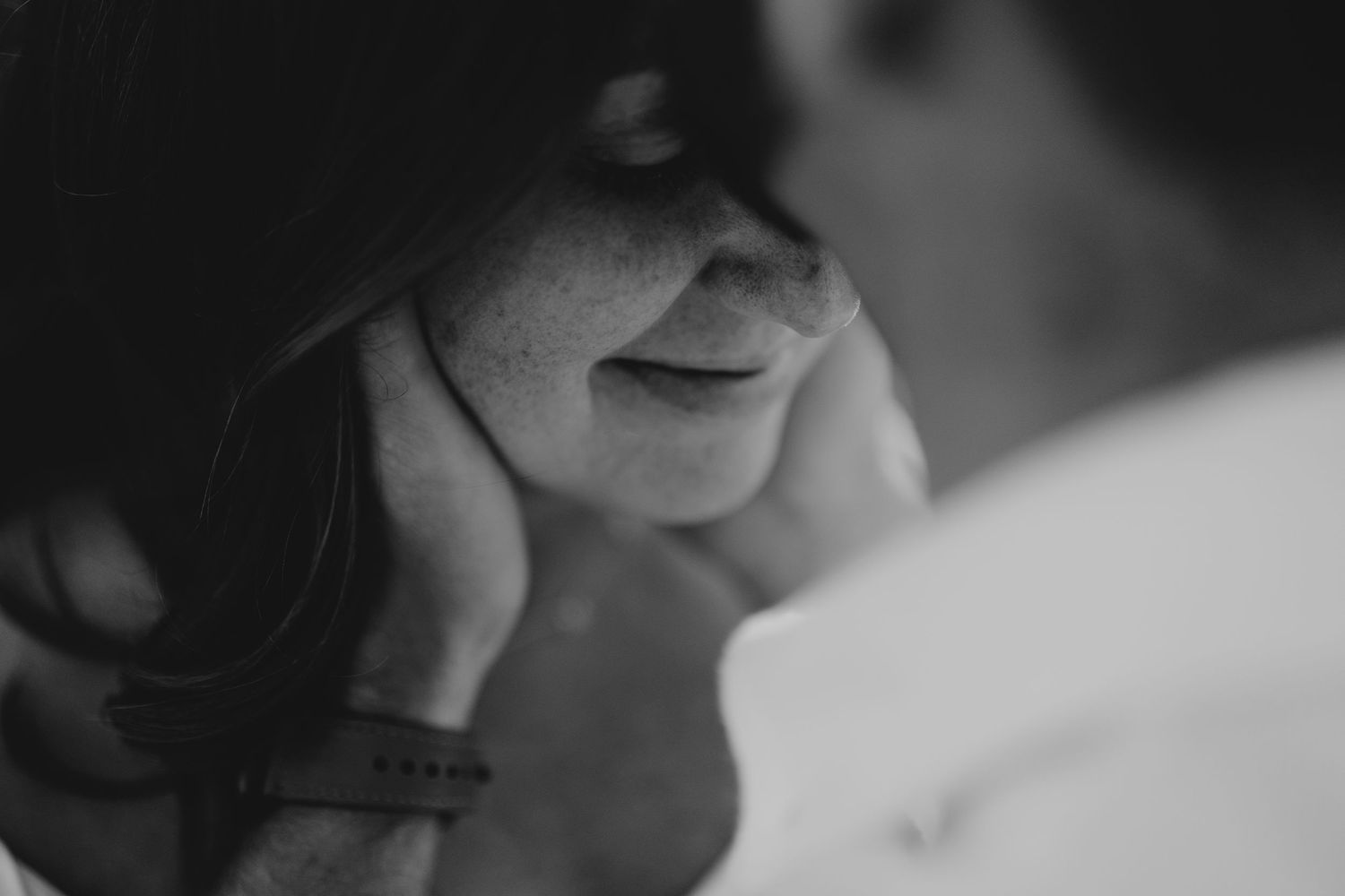 Close-up black and white shot of a couple in an intimate embrace.