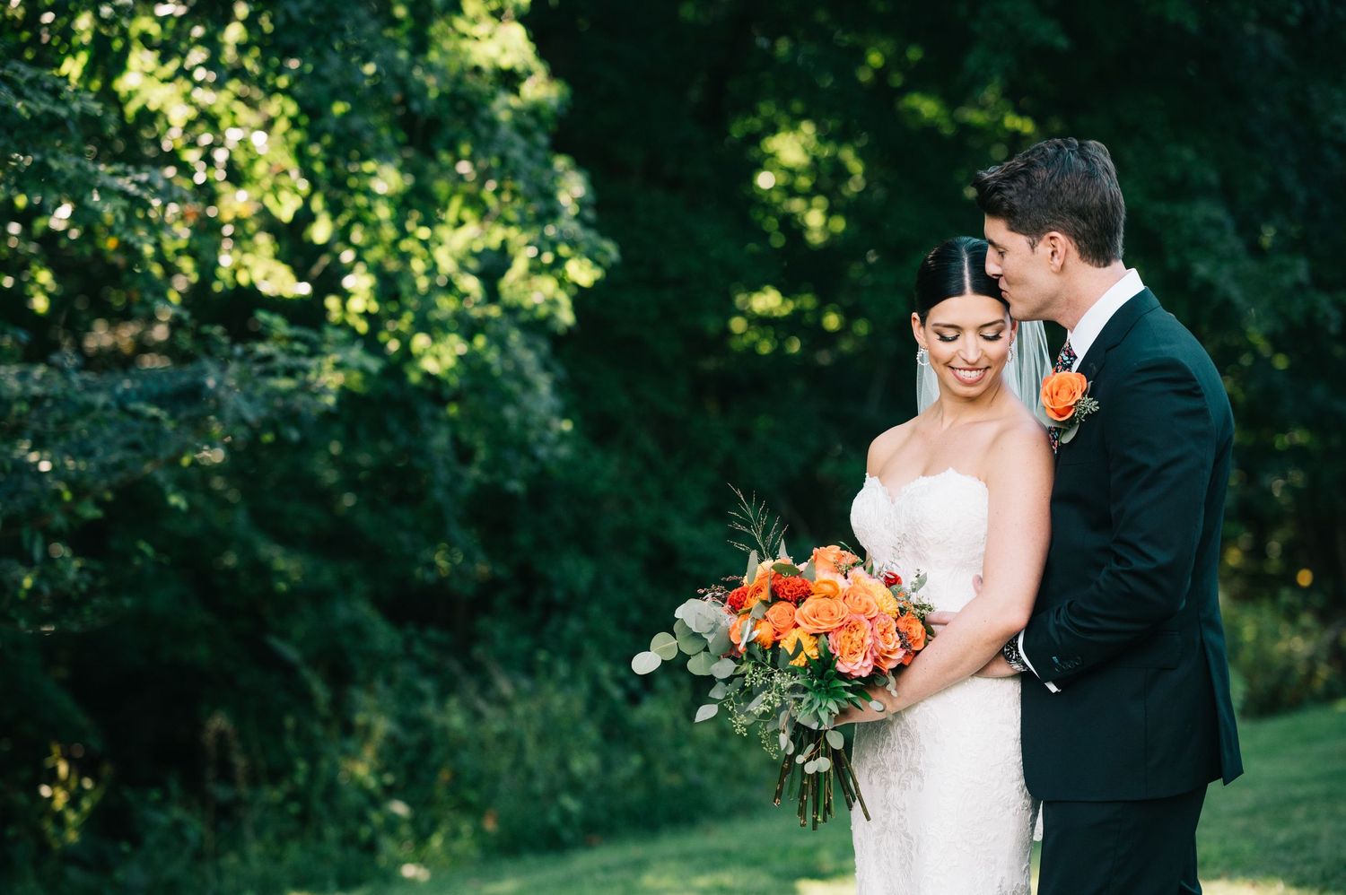 Candid outdoor wedding portraits of couple embracing in sunlit garden setting.