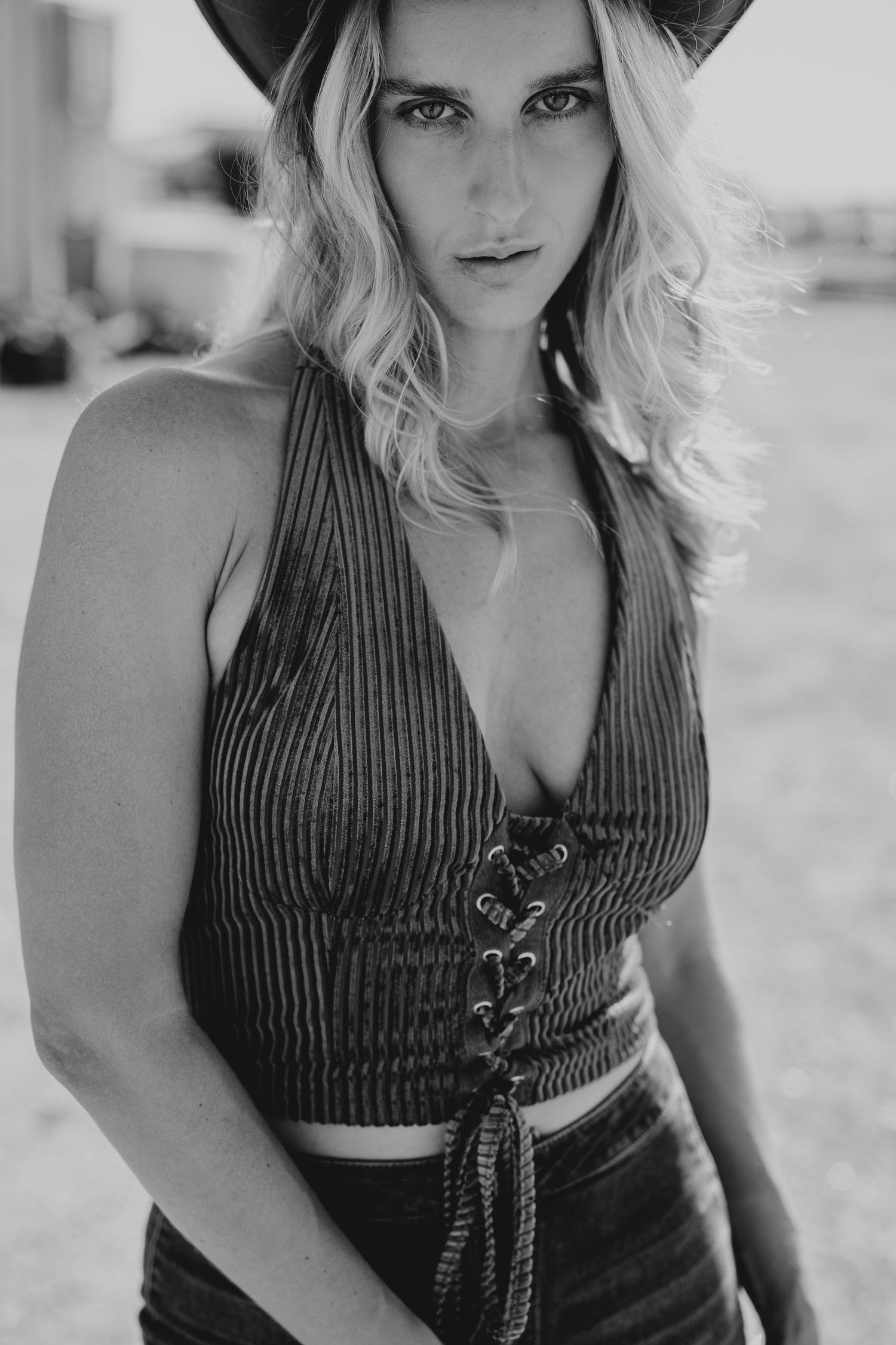 Black and white portrait of blonde woman in cowboy hat and lace-up halter crop top.