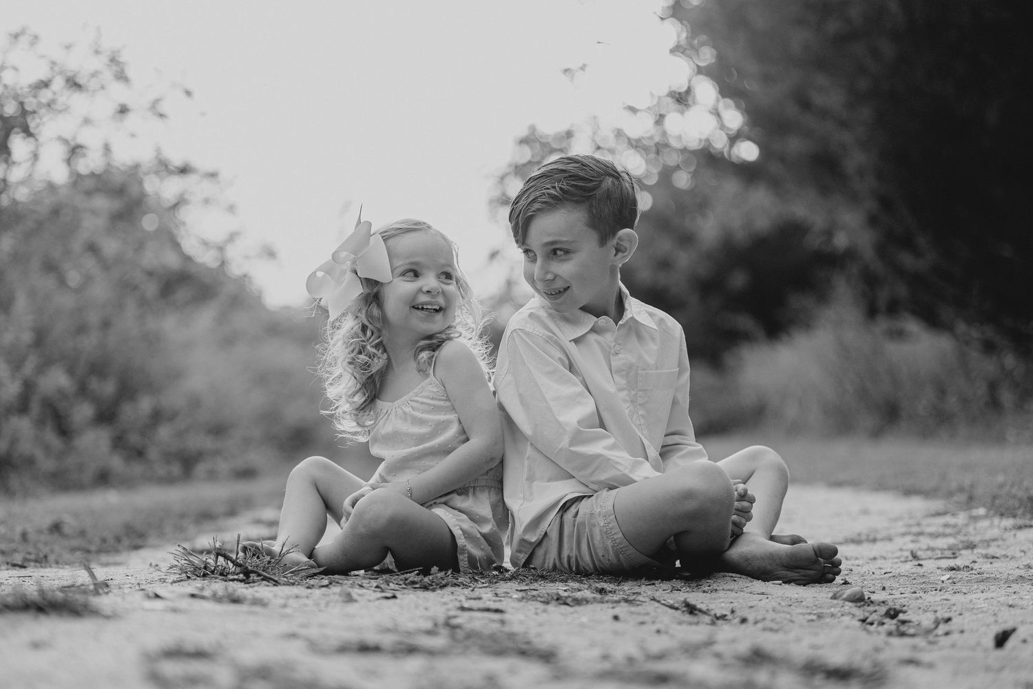 Black and white image of people lying in a grassy field on a sunny day.