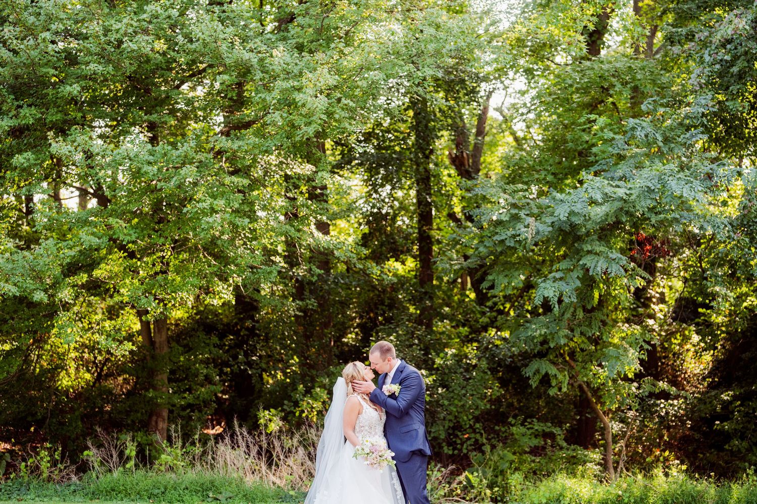 Wedding couple sharing intimate moment in garden setting with natural greenery.