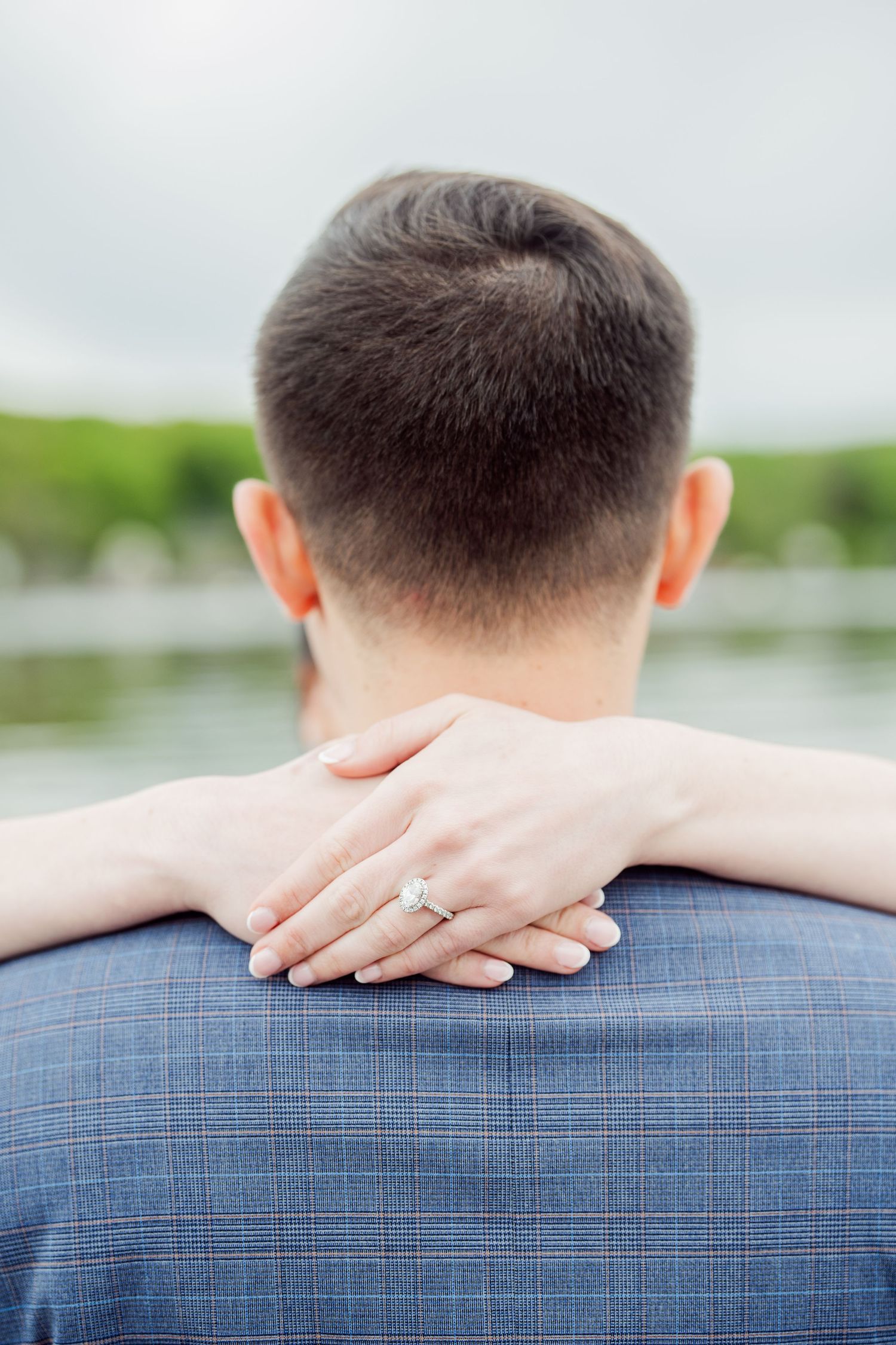 Close-up of hands resting on a blue checkered suit jacket.