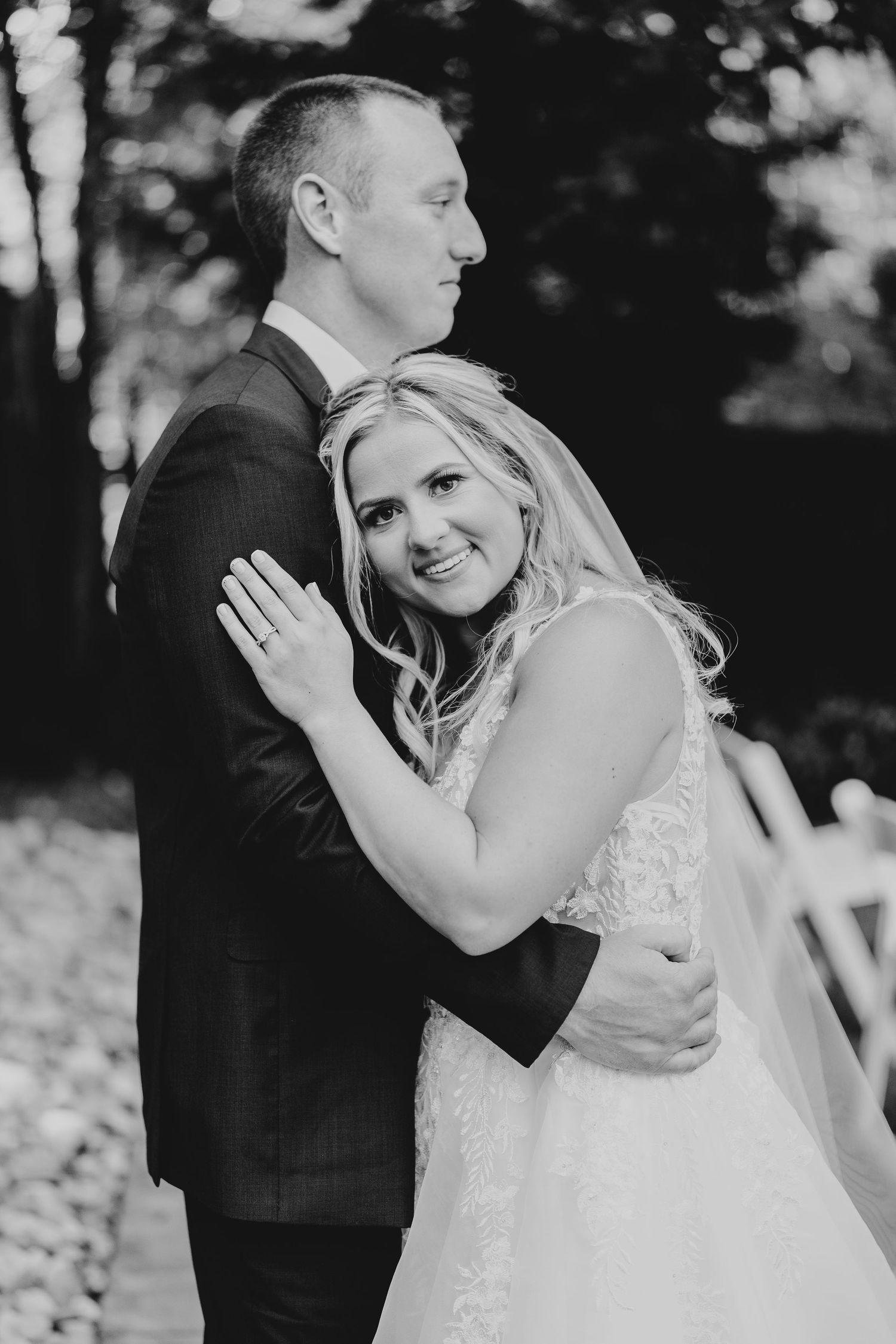 Romantic wedding couple embracing outdoors in black and white photography.