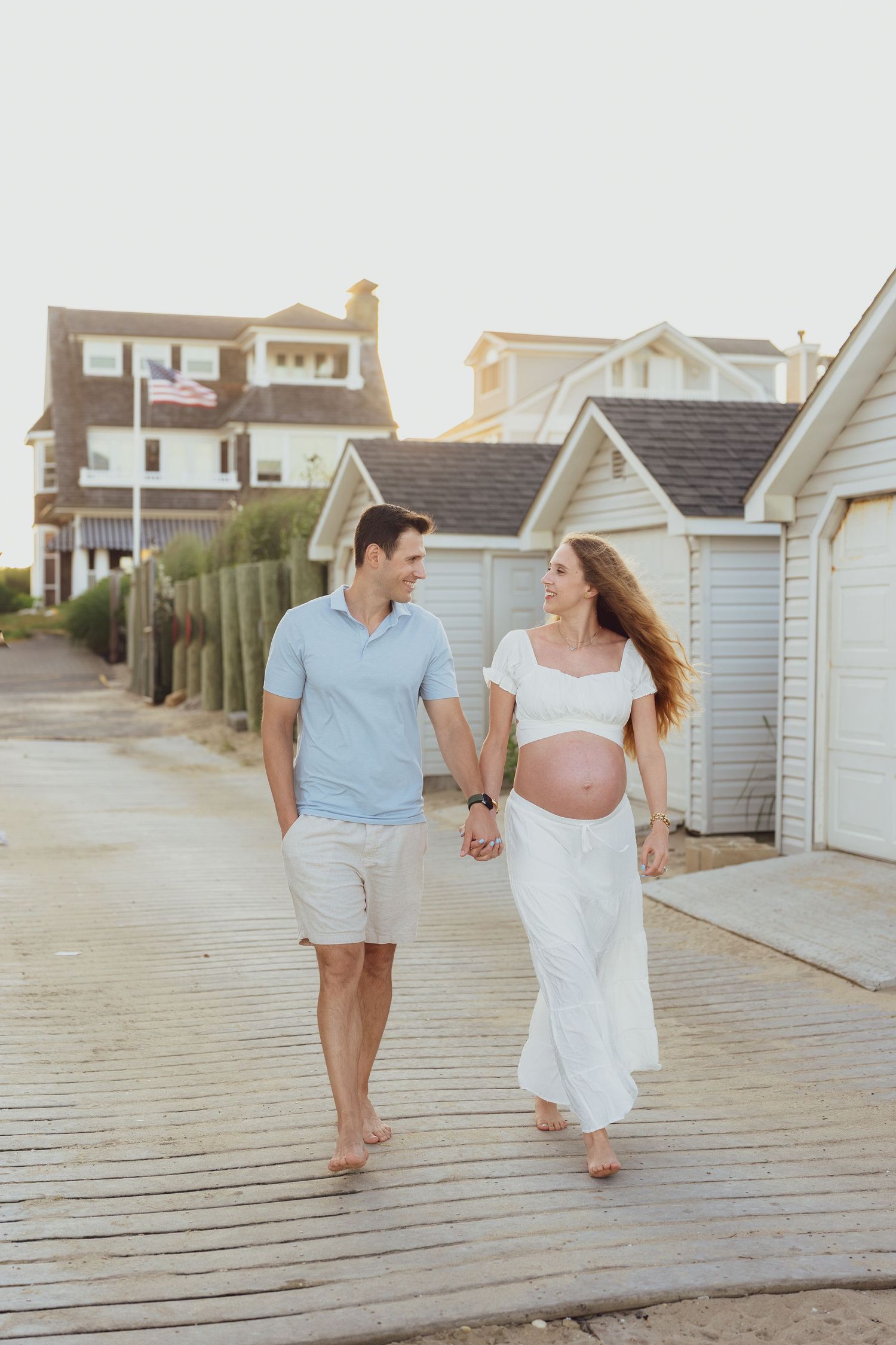 A romantic stroll along a wooden boardwalk near beach houses at dusk.