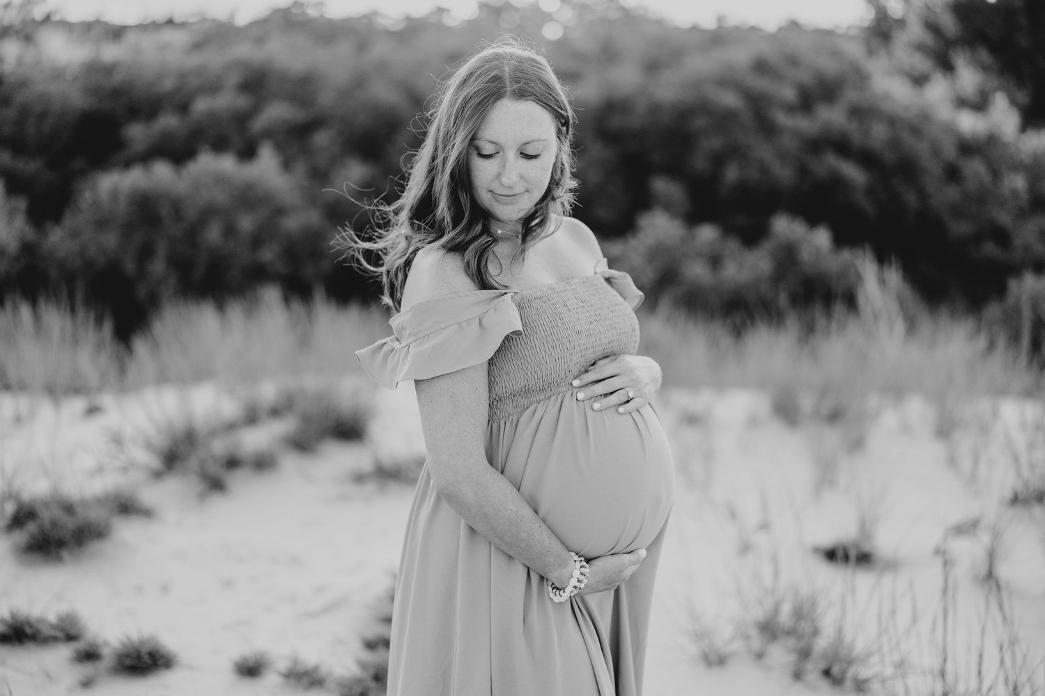 Black and white portrait of a couple embracing in a natural outdoor setting.