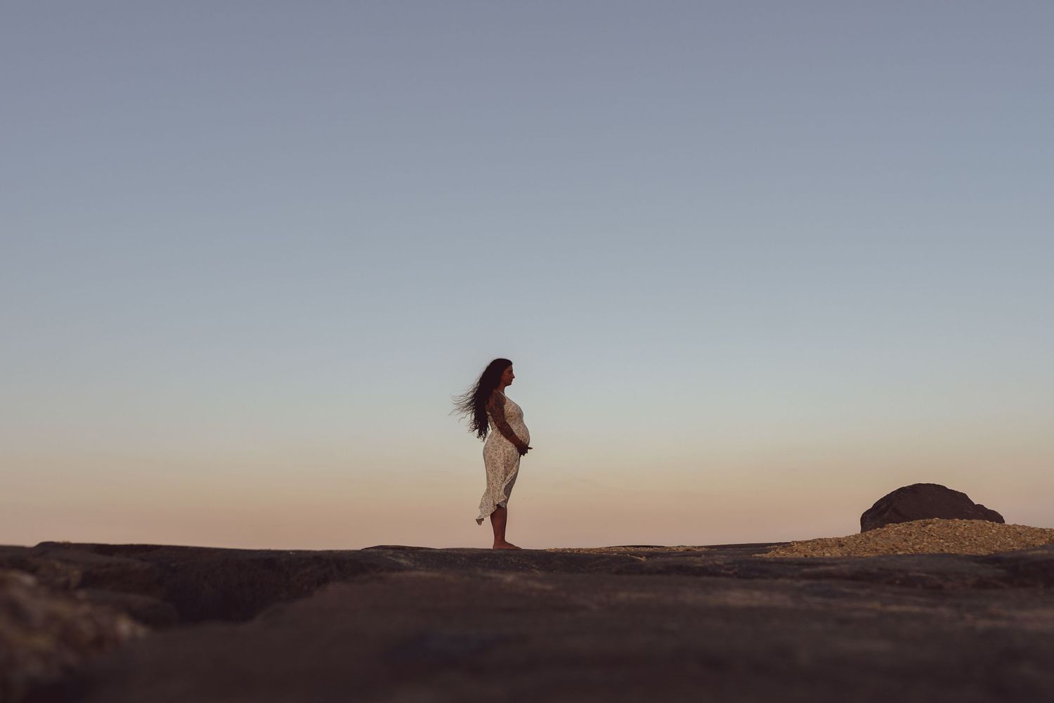 A silhouette of a person standing on a hill during sunset.
