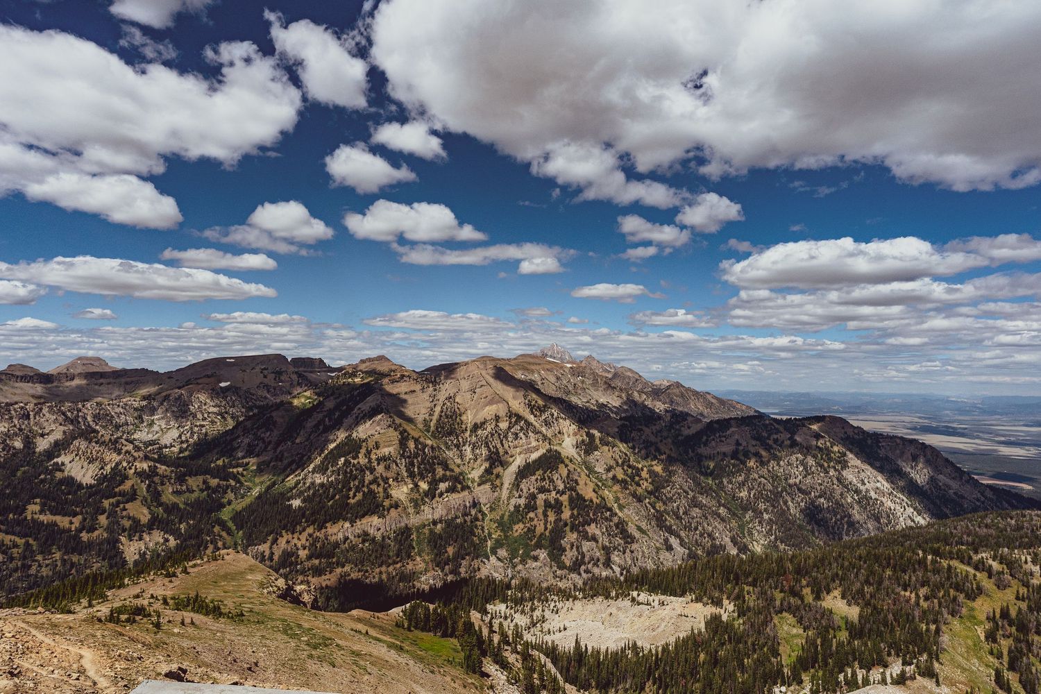 A panoramic view of rugged mountain peaks and valleys under a dramatic cloudy sky in a remote wilderness area.
