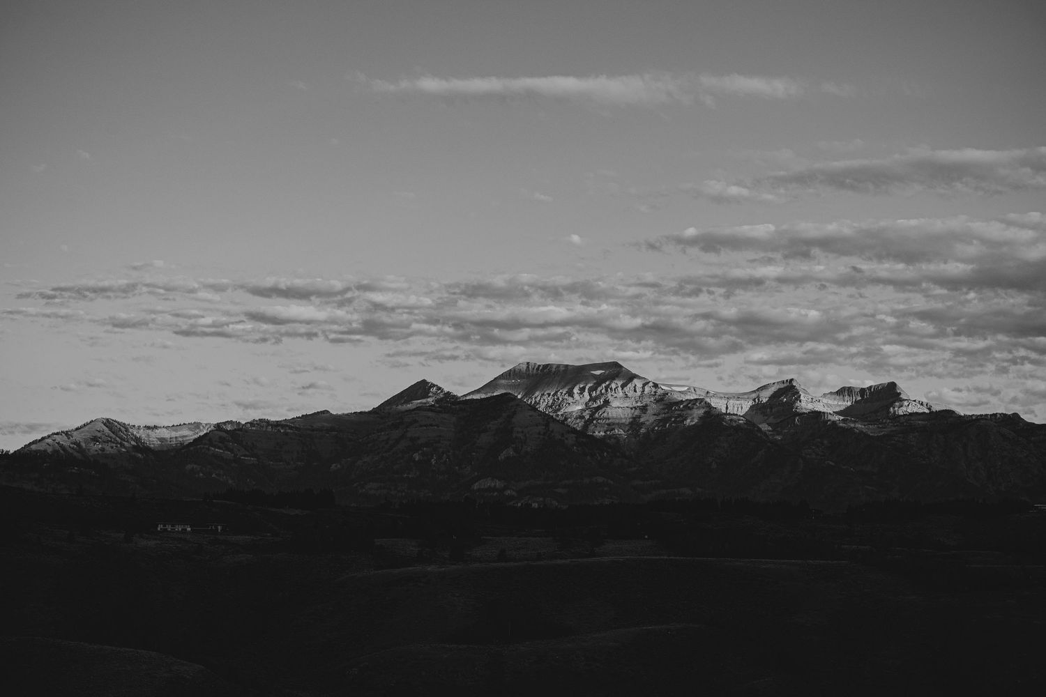 Silhouetted mountain range against a moody grayscale sky at dusk.
