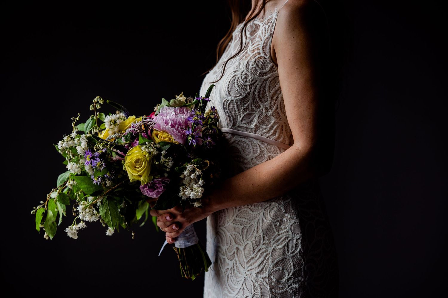 Artistic wedding photos featuring a colorful wildflower bouquet against dark background.