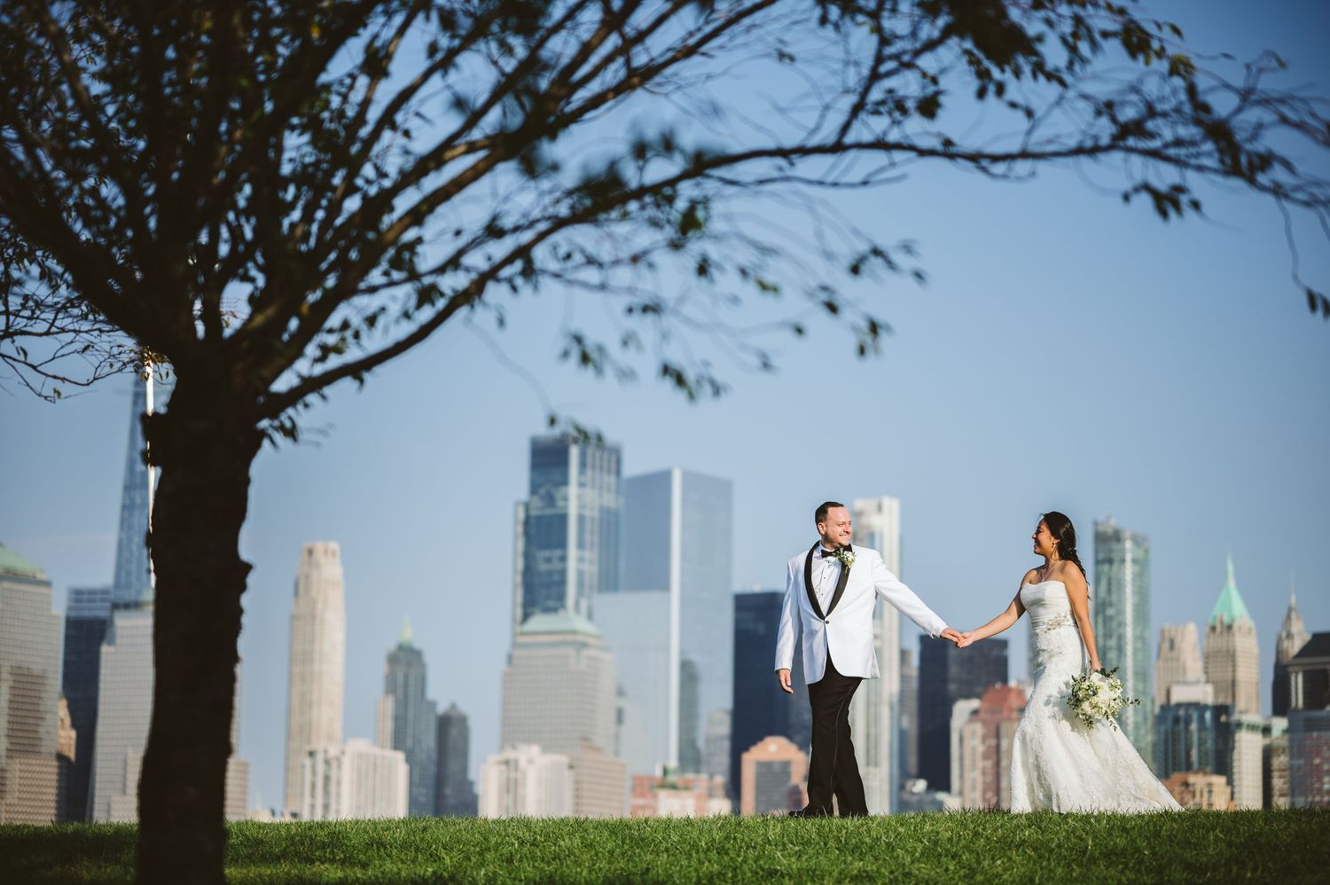 New York City skyline view with fall trees framing a couple on Liberty Island.