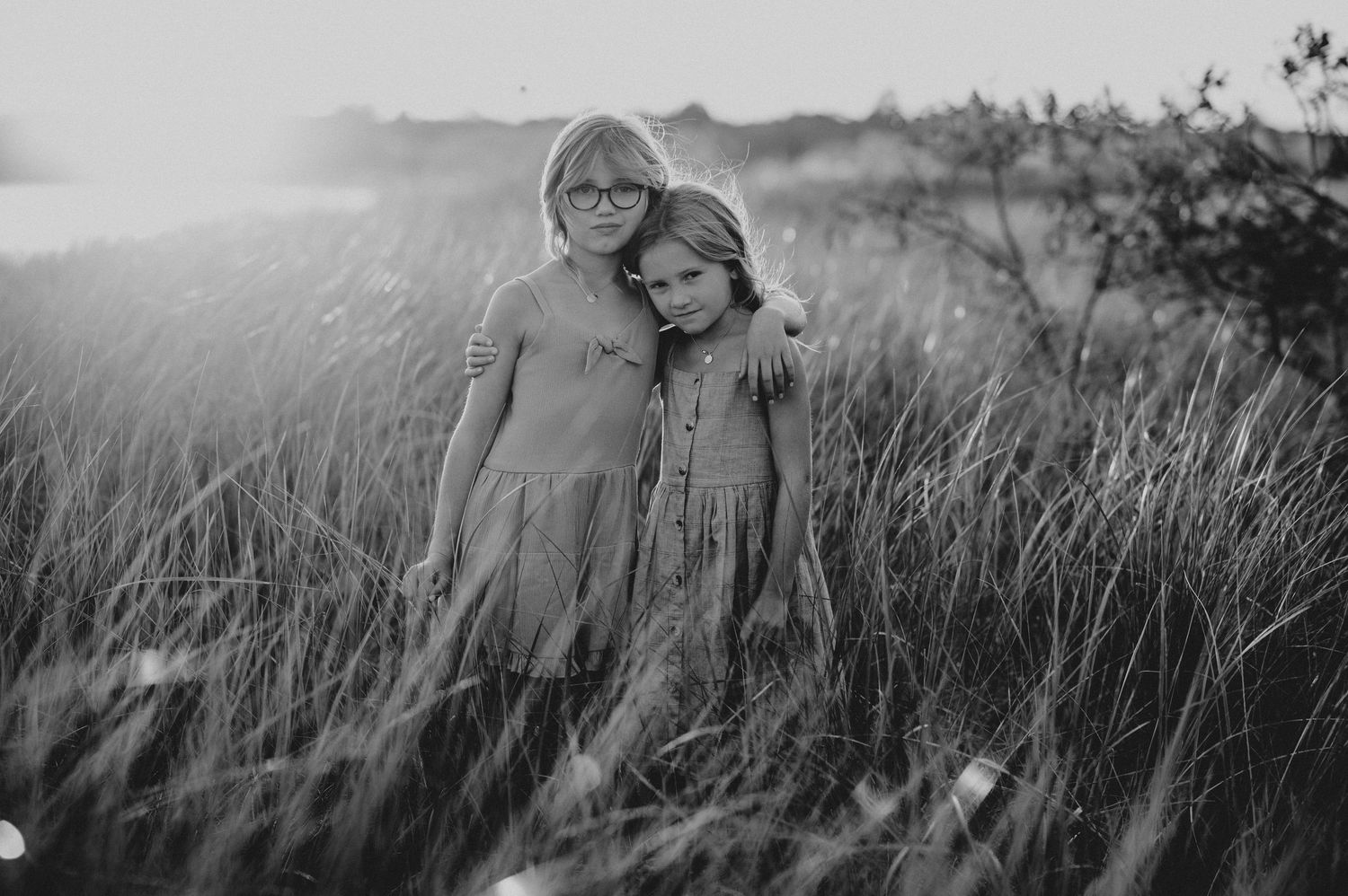 Group silhouetted against tall grass and sky in dramatic black and white photography.