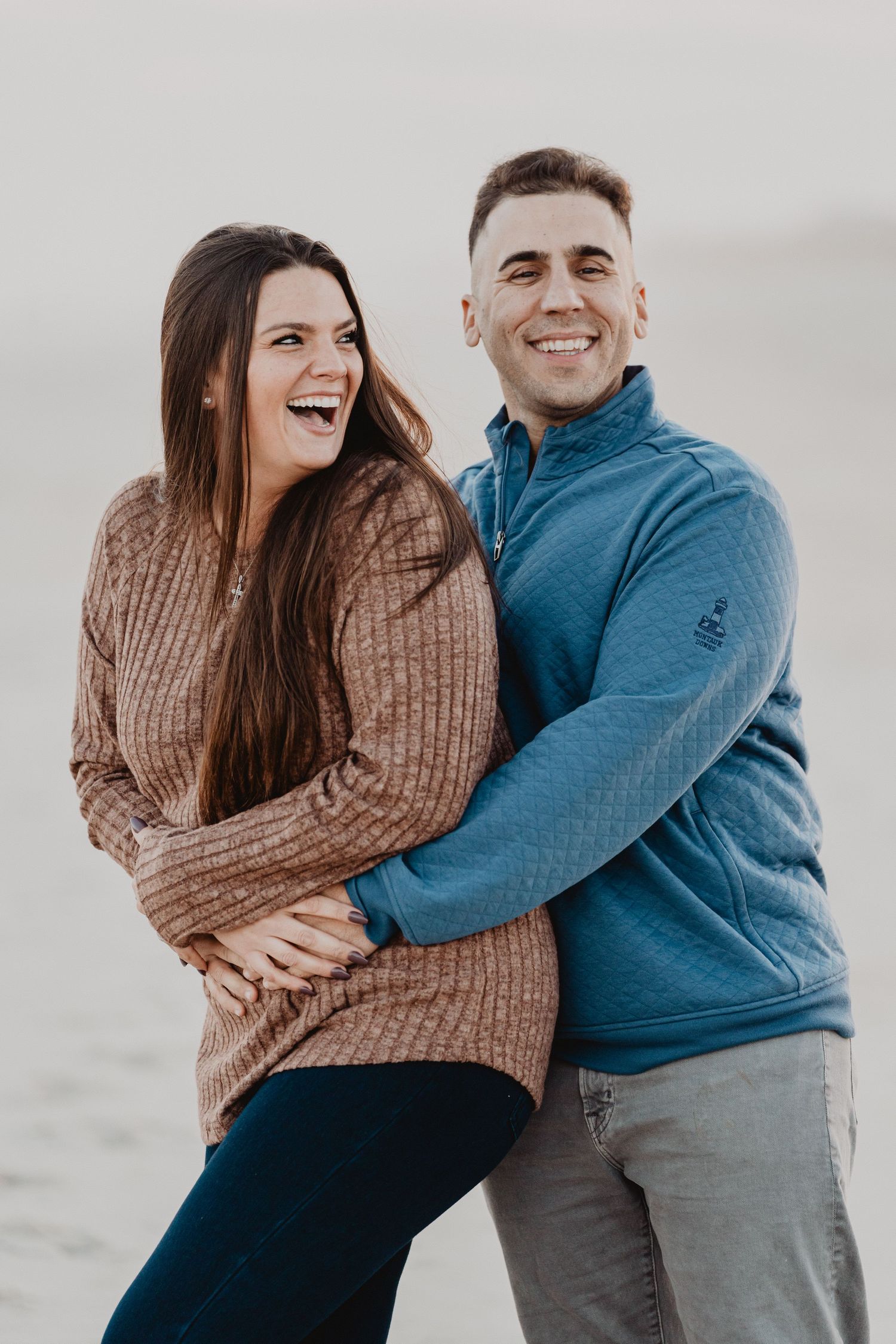 A couple wearing blue and brown sweaters embrace and laugh together in a series of candid outdoor photos.