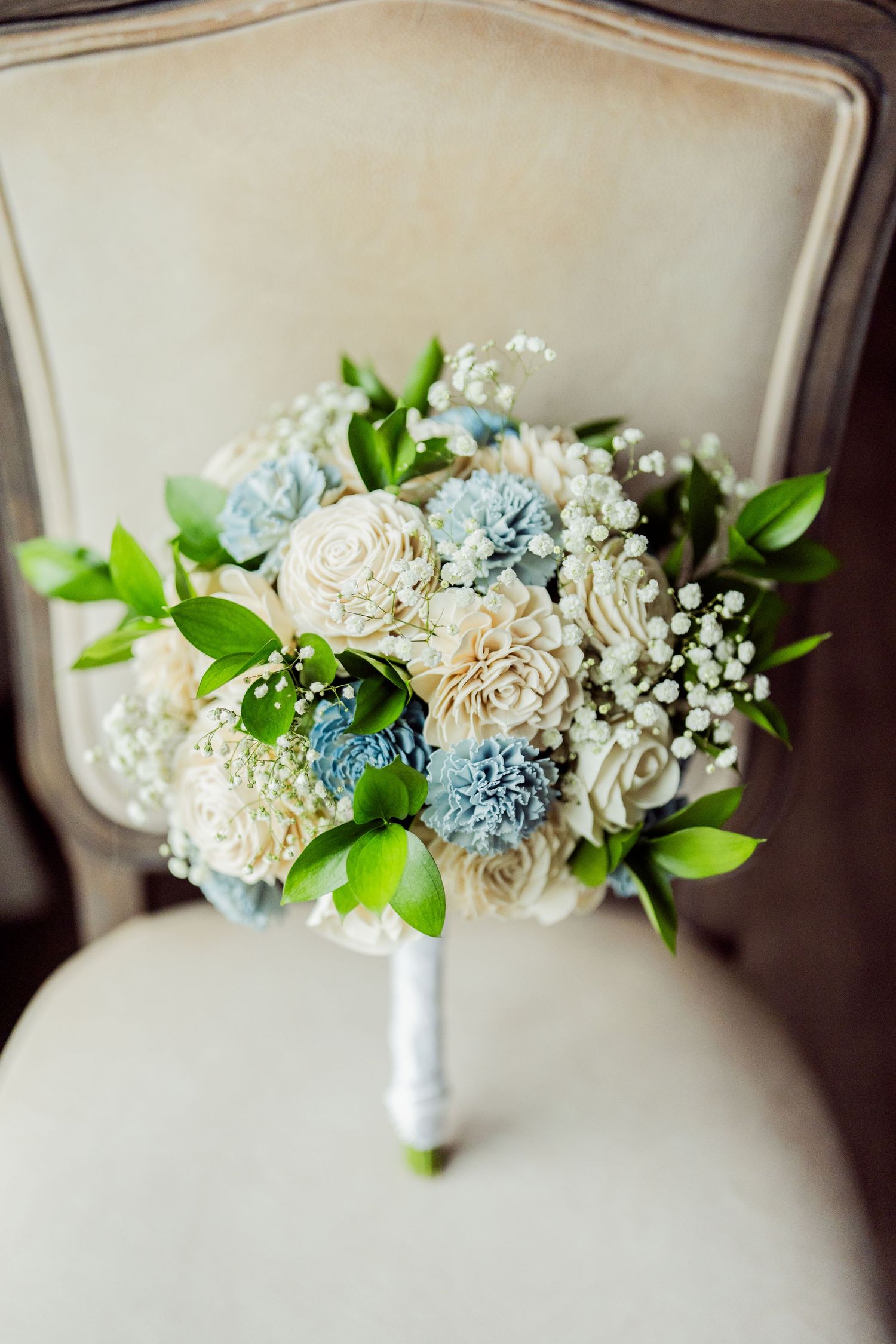 Wedding bouquet with white and light blue flowers accented with baby's breath and greenery.