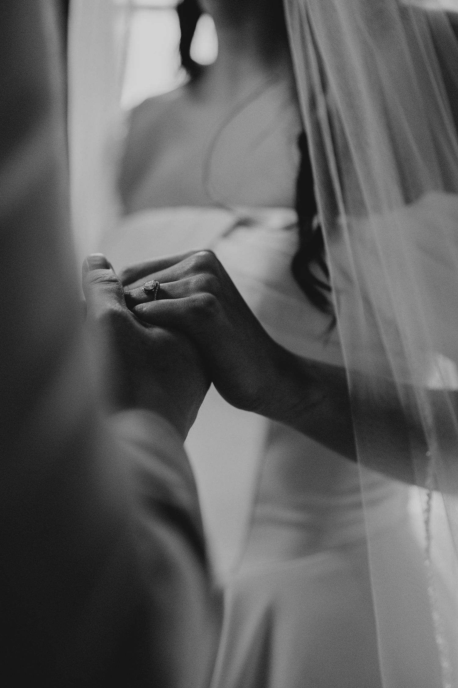 Soft focus black and white image showing delicate details of a wedding veil and dress.