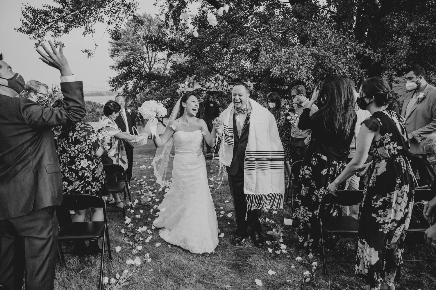 Wedding celebration with guests throwing confetti in garden setting.