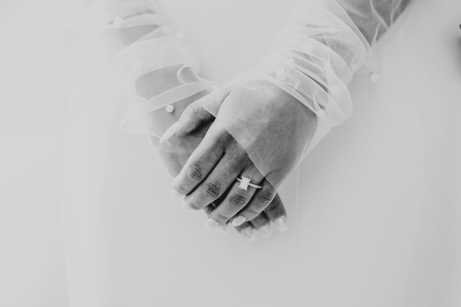 Close-up detail of hands with wedding rings in black and white.